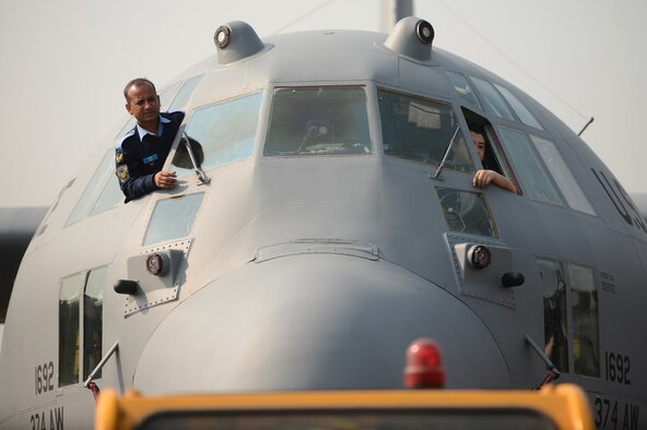 Bangladesh air force Sgt. Jamil Ashraf, left, and U.S. Air Force Senior Airman Yeng Yang monitor a USAF C-130H aircraft as it is towed to a parking position during Exercise COPE SOUTH 15 at BAF Base Bangabandhu, Bangladesh, Jan. 23, 2015. Yang is a C-130H crew chief assigned to the 374th Aircraft Maintenance Squadron at Yokota Air Base, Japan. COPE SOUTH is a Pacific Air Forces-sponsored, bilateral tactical airlift exercise conducted in Bangladesh, with a focus on cooperative flight operations, day and night low-level navigation, tactical airdrop, and air-land missions as well as subject-matter expert exchanges in the fields of operations, maintenance and rigging disciplines. (U.S. Air Force photo by 1st Lt. Jake Bailey/Released)