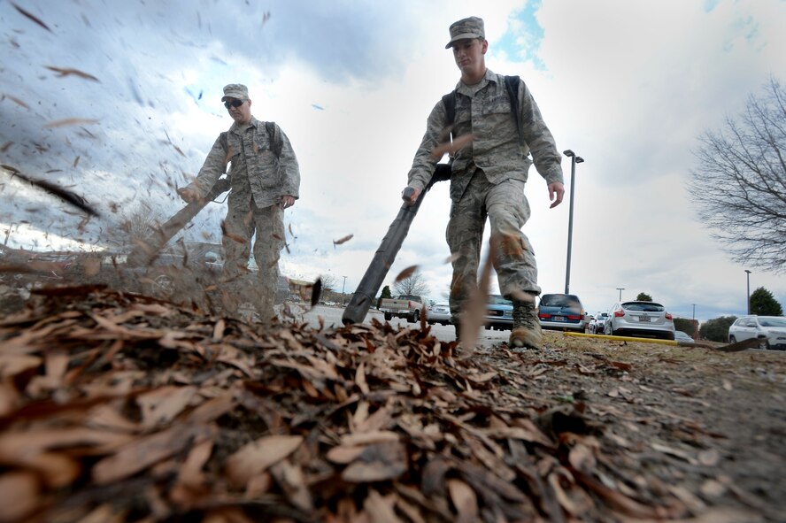 (From left) U.S. Air Force Airmen 1st Class Kyle Newman and Ian Ferguson, 20th Civil Engineer Squadron heavy equipment and pavements apprentices, use leaf blowers to clean the commissary parking lot at Shaw Air Force Base, S.C., Jan. 26, 2015.  Performed once a year at the commissary, 20th CES Airmen removed all leaves and debris to maintain a clean parking lot. (U.S. Air Force photo by Senior Airman Jensen Stidham/Released) 