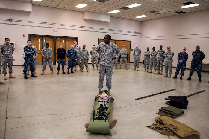 Sergeant First Class Erron Alor, Head Quarters and A Special Troop Battalion Combat Lifesaver instructor, teaches Sailors, Soldiers and Airmen how to transport a person onto a litter Jan. 22, 2015, at Joint Base Charleston, S.C., during a joint services Combat Lifesaver Course. The event was hosted by Soldiers stationed at Fort Jackson, S.C. Forty-three students participated in the course which is designed to teach lifesaving skills to non-medical military personnel. The course is 40 hours long and incorporates classroom and practical training (U.S. Air Force photo/Senior Airman Jared Trimarchi) 