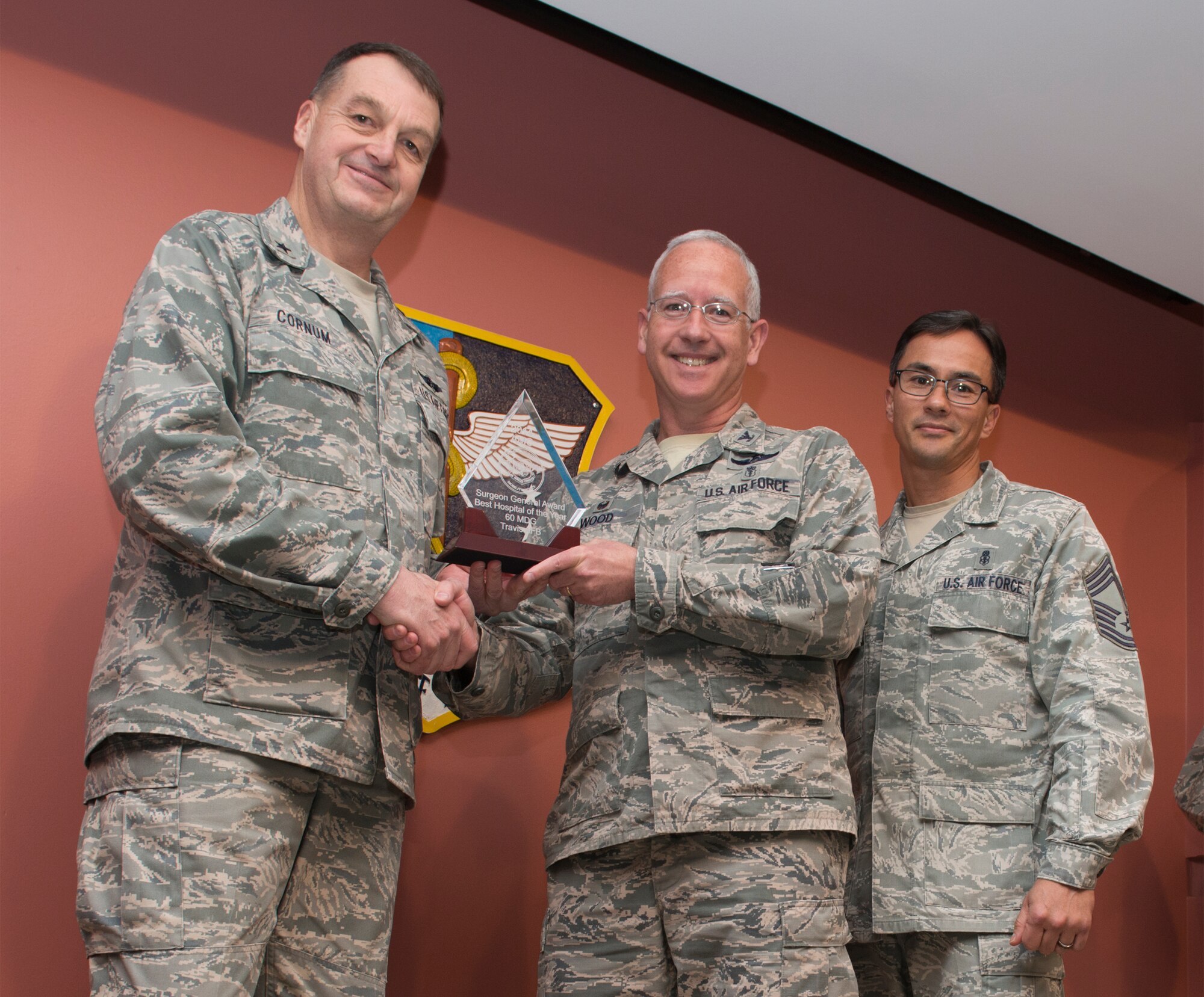 Brig. Gen. Kory Cornum, Air Mobility Command Surgeon, presents Col. Rawson Wood, 60th Medical Group commander, with the Air Mobility Command's Surgeon General Award, Best Hospital of the Year, during an all-call Jan. 15 at David Grant USAF Medical Center. (U.S. Air Force photo/Heide Couch)