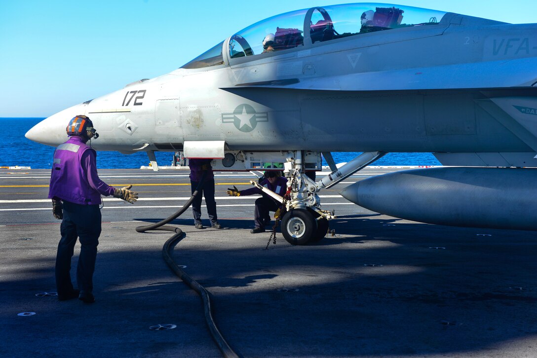 U.S. Navy Petty Officer 1st Class Michael Gonder signals to U.S. Navy Petty Officer 3rd Class Michael McGee while fueling an aircraft aboard the aircraft carrier USS John C. Stennis in the Pacific Ocean, Jan. 24, 2015. Gonder and McGee are aviation boatswains mate fuels.