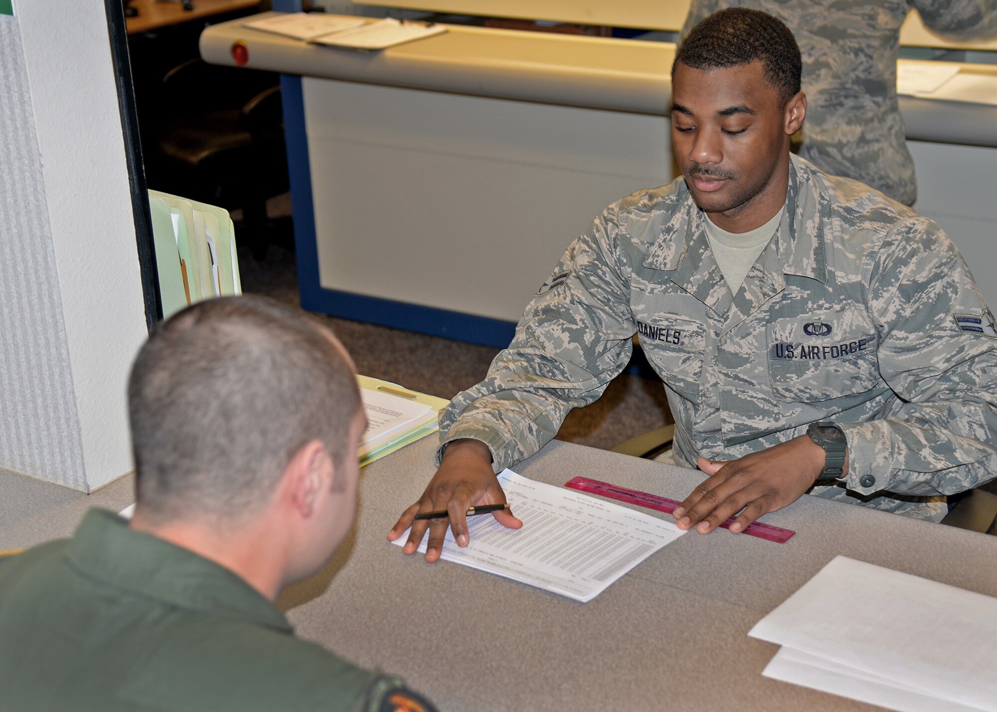 U.S. Air Force Airman 1st Class Leo Daniels, 27th Special Operations Group Aviation Resource Manager, explains daily flight records to a fellow Air Commando Jan. 9 2015 at Cannon Air Force Base, N.M. The 27th SOG was recently announced as the winner of the 2014 Aviation Resource Management Award for large unit. (U.S. Air Force photo/Airman 1st Class Chip Slack)