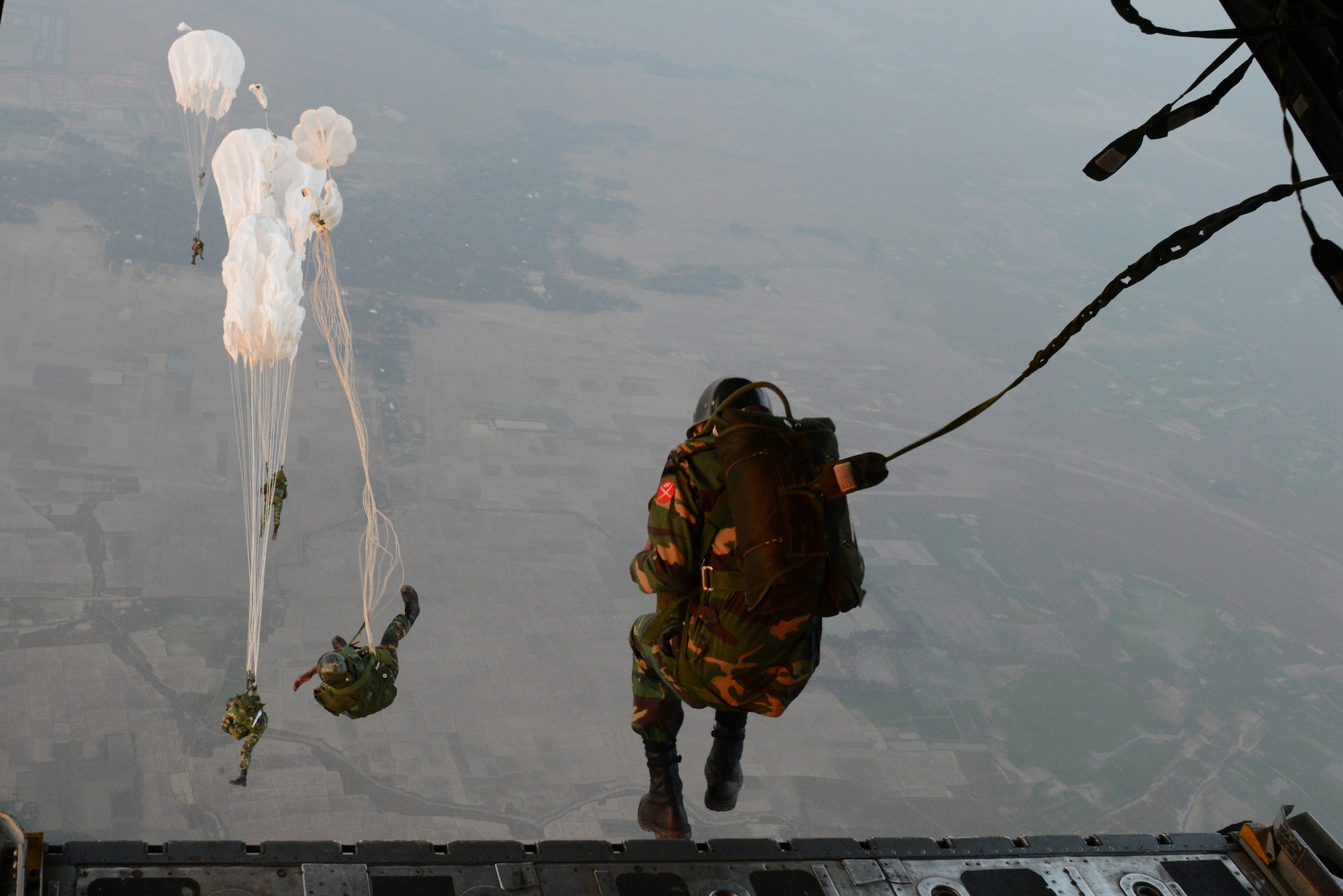 Bangladeshi commandos jump from a U.S. Air Force C-130H aircraft over a drop zone Jan. 24, 2015 during exercise Cope South near Sylhet, Bangladesh. Cope South helps cultivate common bonds, foster goodwill, and improve readiness and compatibility between members of the Bangladesh and U.S. Air Forces. (U.S. Air Force photo/1st Lt. Jake Bailey)