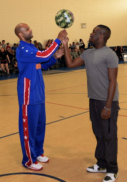 Flight Time, Harlem Globetrotter point guard, helps C.J. Taylor, Team Barksdale member, spin a ball on his finger on Barksdale Air Force Base, La., Jan. 26, 2015. Flight Time has been with the Globetrotters longer than any other current player and has shot hoops with President Barack Obama at the annual White House Easter Egg Roll. The Globetrotters' 30-player team participates in more than 350 shows per year. (U.S. Air Force photo/Airman 1st Class Curt Beach)