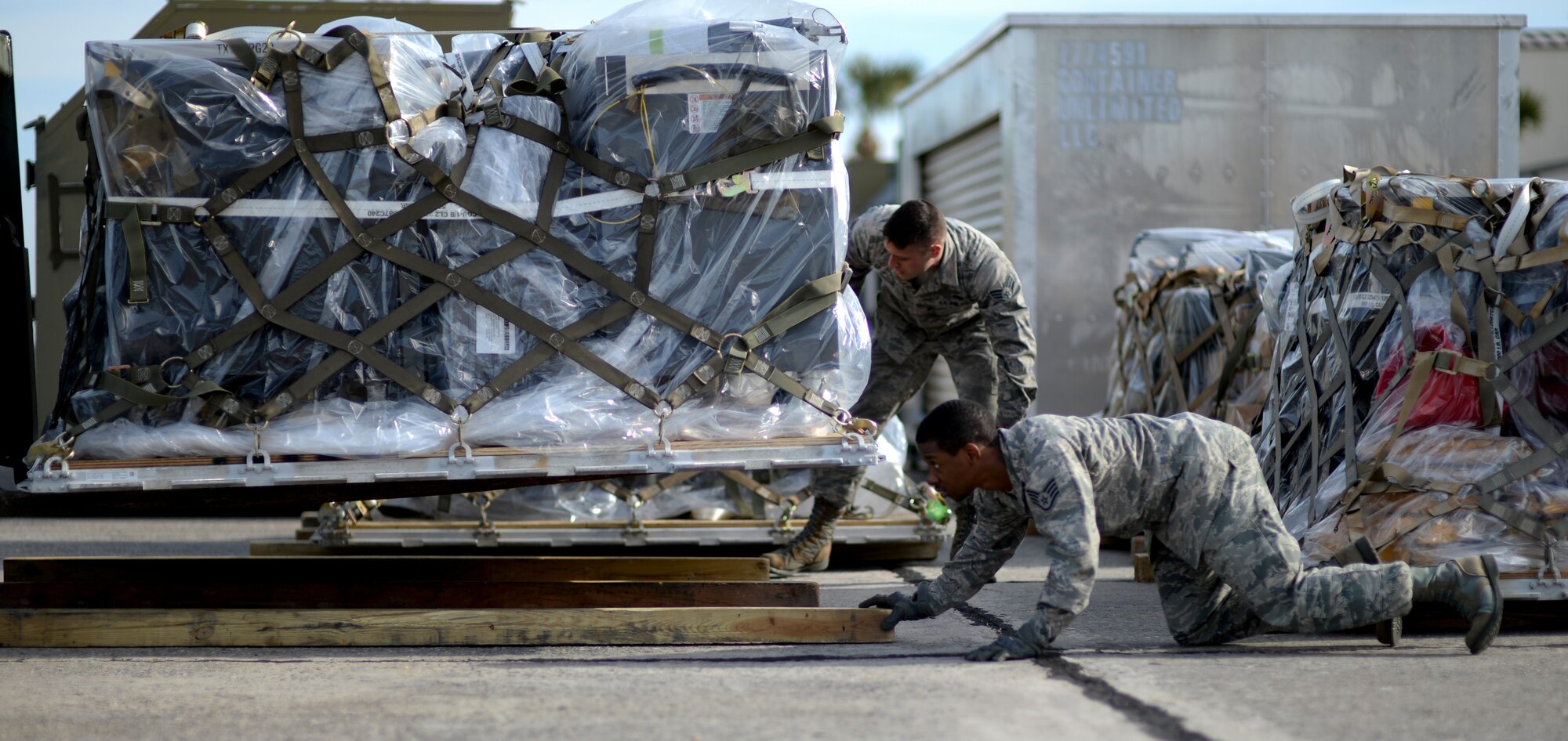 Staff Sgt. Kaylon Haynes, 325th Logistics and Readiness Squadron vehicle operator, places a board under a pallet being lowered to the ground on the Tyndall flightline Jan 14. The pallet was brought to the 95th Fighter Squadron as part of an exercise conducted by Tyndall to train and project unrivaled combat air power.  (U.S. Air Force photo by Airman 1st Class Dustin Mullen/Released)