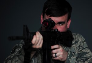 U.S. Air Force Staff Sgt. Ryan Gulley, 633rd Security Forces Squadron training instructor, fires at a simulated target at Langley Air Force Base, Va., Jan. 26, 2015. The new firearms simulator allows Airmen to gain real-world knowledge and experience through projections of real-life scenarios. (U.S. Air Force photo by Airman 1st Class Areca T. Wilson/Released) 