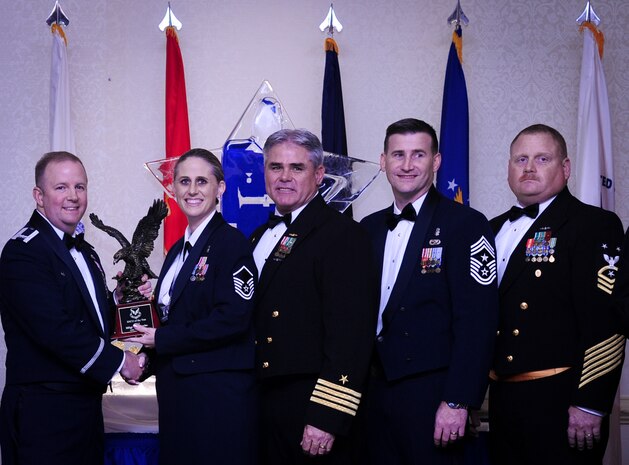 Col. Jeffrey DeVore, Joint Base Charleston commander, Capt. Timothy Sparks, JB Charleston deputy commander, Master Chief Petty Officer Joseph Gardner, Naval Support Activity command master chief and Chief Master Sgt. Mark Bronson, 628th Air Base Wing command chief present Master Sgt. Kari Boyles, 628th Aerospace Medicine Squadron, with the SNCO of the Year award Jan. 23, 2015, at the 2015 628th ABW Annual Awards Banquet at the Charleston Club on Joint Base Charleston, S.C. (U.S. Air Force photo/Airman 1st Class Clayton Cupit)