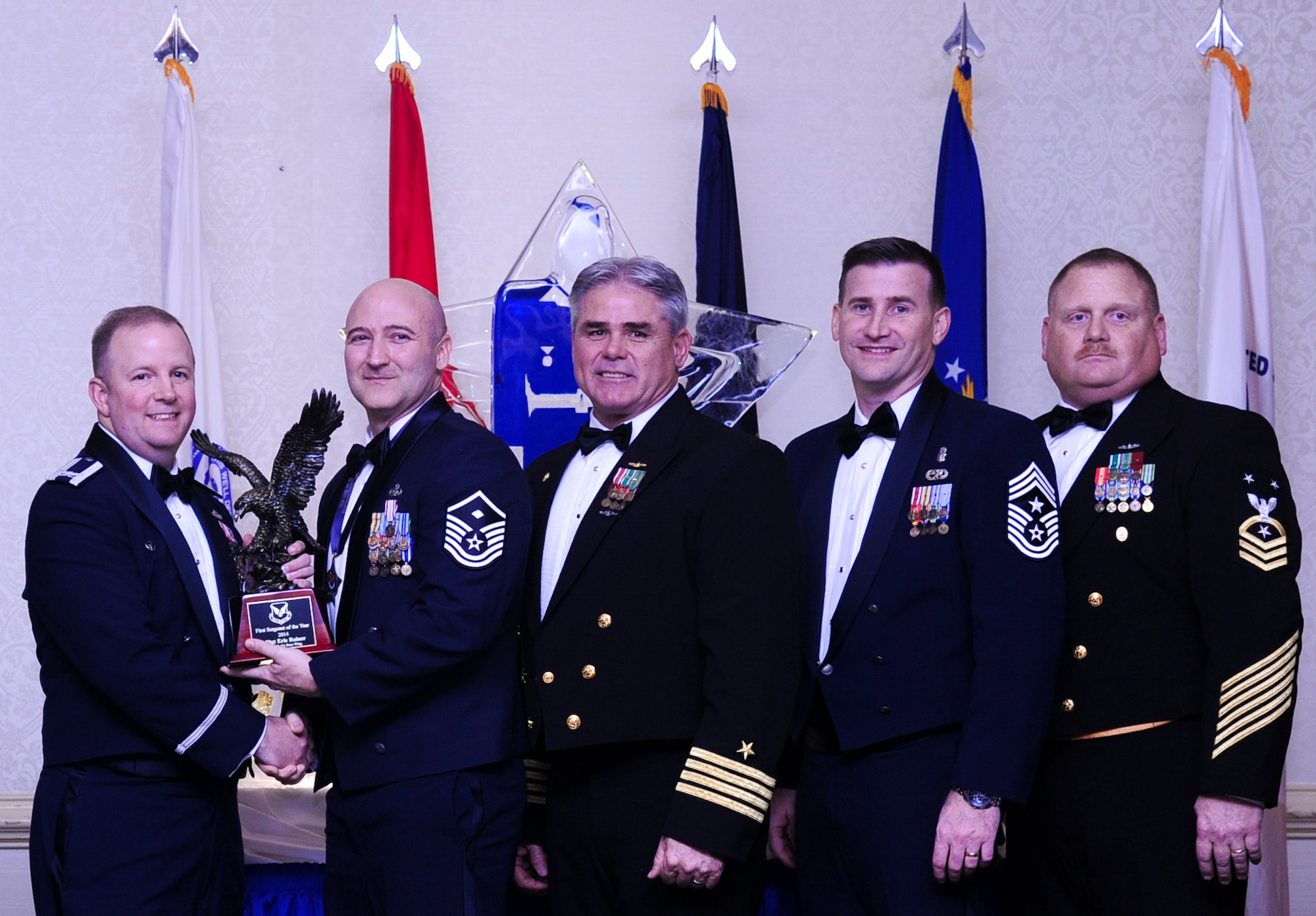 Col. Jeffrey DeVore, Joint Base Charleston commander, Capt. Timothy Sparks, JB Charleston deputy commander, Master Chief Petty Officer Joseph Gardner, Naval Support Activity command master chief and Chief Master Sgt. Mark Bronson, 628th Air Base Wing command chief present Master Sgt. Eric Rainer, 628th Medical Group, with the First Sergeant of the Year award Jan. 23, 2015, at the 2015 628th ABW Annual Awards Banquet at the Charleston Club on Joint Base Charleston, S.C. (U.S. Air Force photo/Airman 1st Class Clayton Cupit)