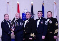 Col. Jeffrey DeVore, Joint Base Charleston commander, Capt. Timothy Sparks, JB Charleston deputy commander, Master Chief Petty Officer Joseph Gardner, Naval Support Activity command master chief and Chief Master Sgt. Mark Bronson, 628th Air Base Wing command chief present Master Sgt. Eric Rainer, 628th Medical Group, with the First Sergeant of the Year award Jan. 23, 2015, at the 2014 628th ABW Annual Awards Banquet at the Charleston Club on Joint Base Charleston, S.C. (U.S. Air Force photo/Airman 1st Class Clayton Cupit) 
