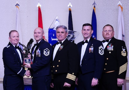 Col. Jeffrey DeVore, Joint Base Charleston commander, Capt. Timothy Sparks, JB Charleston deputy commander, Master Chief Petty Officer Joseph Gardner, Naval Support Activity command master chief and Chief Master Sgt. Mark Bronson, 628th Air Base Wing command chief present Master Sgt. Eric Rainer, 628th Medical Group, with the First Sergeant of the Year award Jan. 23, 2015, at the 2015 628th ABW Annual Awards Banquet at the Charleston Club on Joint Base Charleston, S.C. (U.S. Air Force photo/Airman 1st Class Clayton Cupit)