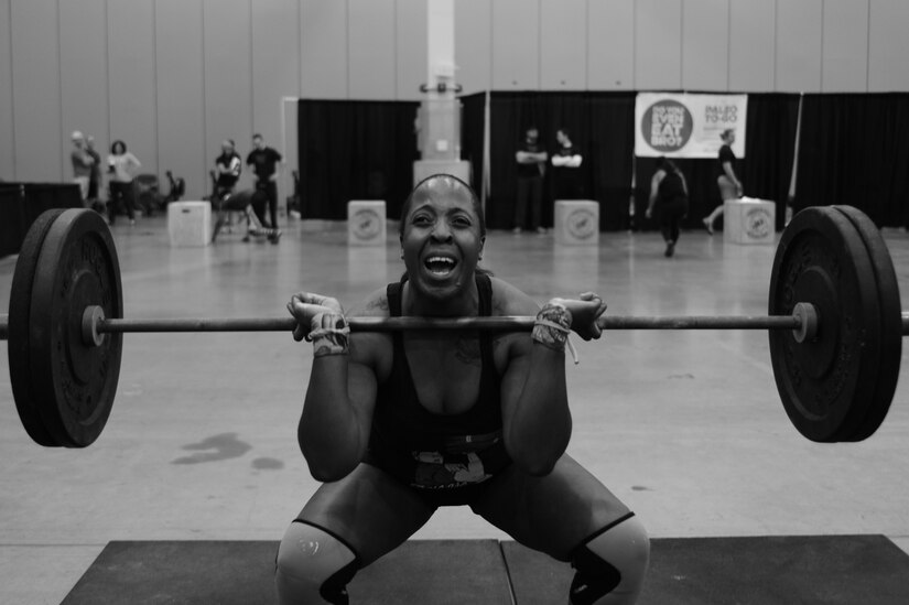 U.S. Air Force Staff Sgt. Paris Roberts, Air Combat Command Public Affairs knowledge operations manager, performs a front squat at the TeamGrit CrossFit competition in Hampton, Va., Jan. 17, 2015. This heat involved a timed competition performing twelve front squats, bear crawling and sprinting. (U.S. Air Force photo by Staff Sgt. Natasha Stannard/Released)