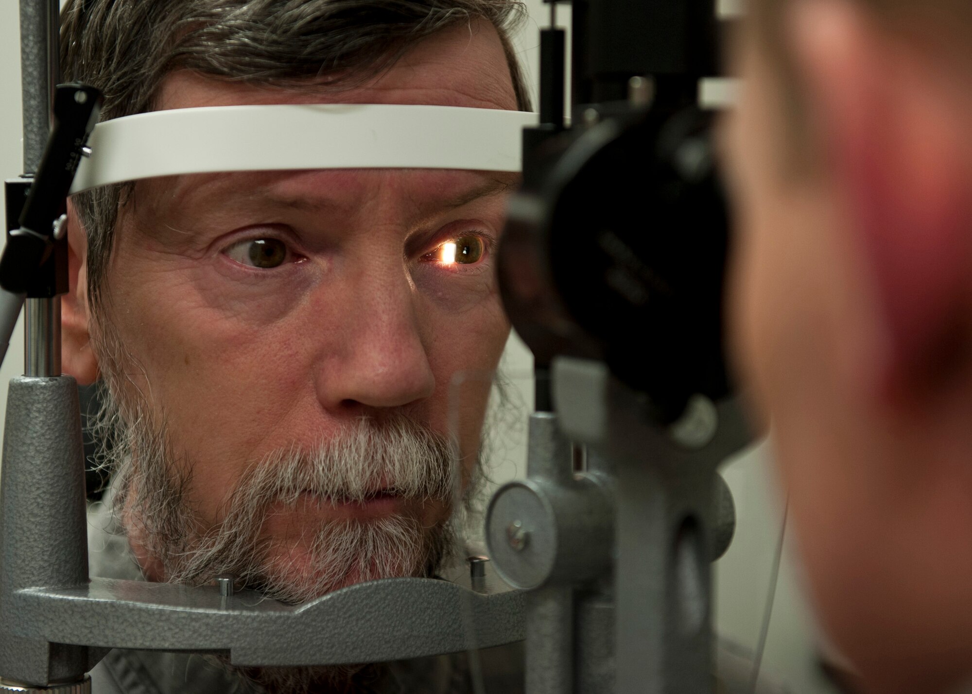 PETERSON AIR FORCE BASE, Colo. – Gordan Dixon, an optometry patient, gets his eyes checked by Maj. Chad Willis, 21st Aerospace Medical Squadron chief of aerospace optometry at the optometry clinic, Jan. 16, 2015. The optometry clinic ensures active-duty personnel are visually qualified for worldwide assignment and for the performance of their Air Force jobs. The optometry clinic is now in the temporary facility next to building 959, the main clinic. (U.S. Air Force photo by Senior Airman Tiffany DeNault)