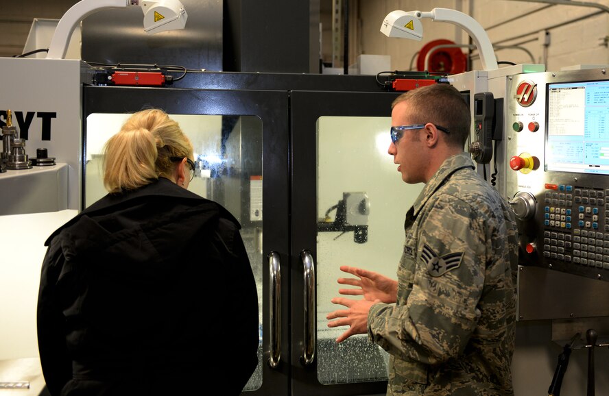 Senior Airman David Reid, 2nd Maintenance Squadron metals technician journeyman, demonstrates the capabilities of a computer numerically-controlled machine to retired Chief Master Sgt. Athena Cody, wife of Chief Master Sgt. of the Air Force James Cody, on Barksdale Air Force Base, La., Jan. 23, 2015. The machine can create an aircraft part in several minutes that would otherwise take an eight-hour shift to complete by hand. (U.S. Air Force photo/Airman 1st Class Curt Beach)