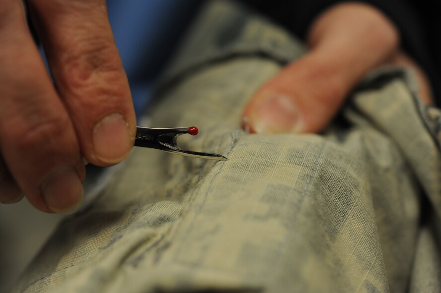 Michelle Offman, alterations shop concessionaire, removes name tapes from an Airman battle uniform blouse at the clothing alterations shop on Minot Air Force Base, N.D., Jan. 21, 2015. Located in the Base Exchange, the shop offers a wide variety of tailoring services to civilians, Airmen and their dependents. (U.S. Air Force photo/Senior Airman Stephanie Morris)