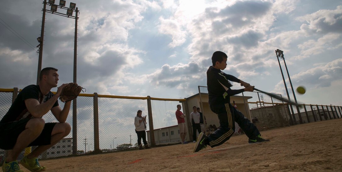 Shosuke Kokuba, right, swings as Cpl. Eric D. Chrivia catches during a friendly softball game between the Henoko Young Men’s Association and U.S. Marines Jan. 25 on Camp Schwab. The Young Men’s Association played the Marines in a nine-inning game. Kokuba, from Henoko, Okinawa, is a member of the Henoko Young Men’s Association. Chrivia, from Hale, Michigan, is a mortarman with 3rd Battalion, 3rd Marine Regiment, currently assigned to 4th Marine Regiment, 3rd Marine Division, III Marine Expeditionary Force under the unit deployment program.