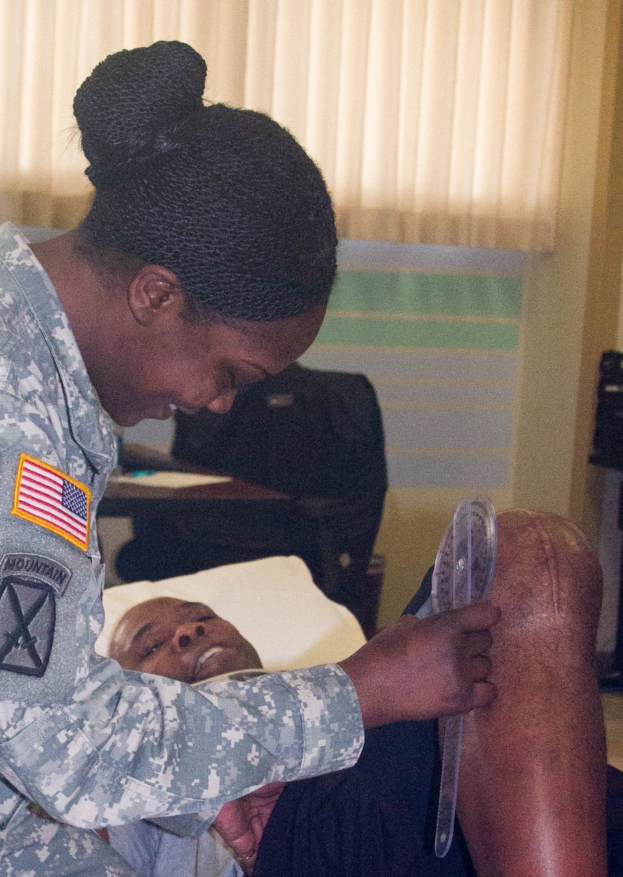 Army Sgt. Latonya Sharp, a physical therapy technician at Madigan Army Medical Center on Joint Base Lewis-McChord, Wash., measures the range of motion in the right knee of Master Sgt. Marvin Howard, a mechanical maintenance supervisor who had a total knee replacement. U.S. Army photo by Staff Sgt. Patricia McMurphy