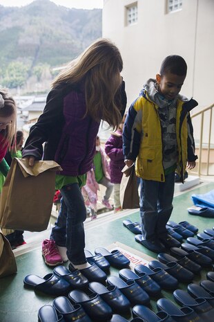 Children from the School Age Care center aboard Marine Corps Air Station Iwakuni, Japan, put on slippers provided by the Nishiki Seiryu Elementary School in Iwakuni City before entering the building, Jan. 23, 2015. SAC visited the school to compare Japanese and American schooling.