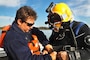Jeffrey Pardee, Panamerican diver tender, examines diver James Duff’s equipment and topside air supply during an initial dive event Jan. 22, 2015, on the Savannah River near Old Fort Jackson. Duff, a Panamerican diver and maritime archaeologist, used a rope to connect sections of the CSS Georgia wreck site scuttled on the river floor.  A network of ropes connects wreck site artifacts and assists divers to navigate through the mucky underwater floor of the Savannah River. CSS Georgia recovery is the first action begun under the construction phase of the Savannah Harbor Expansion Project (U.S. Army Corps of Engineers photo by Chelsea Smith.)