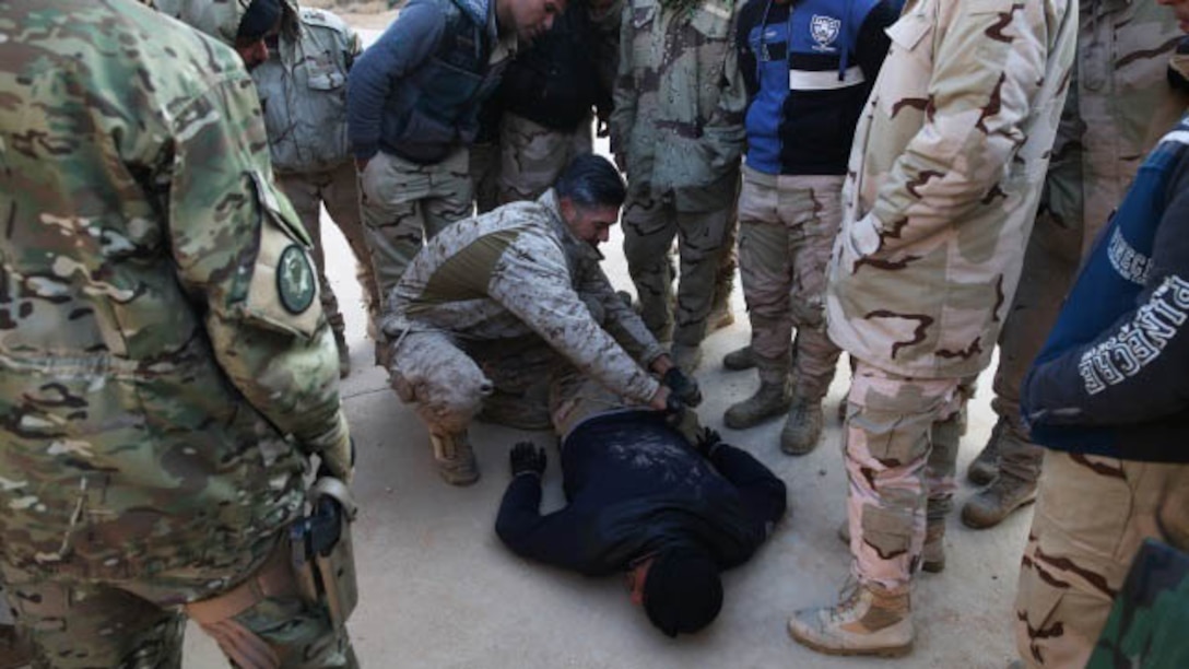 U.S. Marine Chief Warrant Officer 2 Juan Rodriguez, Explosive Ordnance Disposal Officer with Special Purpose Marine Air Ground Task Force-Crisis Response-Central Command, Task Force Al Asad, gives a Counter Improvised Explosive Device class and shows Iraqi soldiers how to properly check a casualty for explosive traps at Al Asad Air Base, Iraq, Jan. 18, 2015. Rodriguez is the lead for CIED training in the Build Partnership Capacity program designed to equip Iraqi Army units with the training and knowledge necessary to degrade and defeat Daesh in Iraq. 