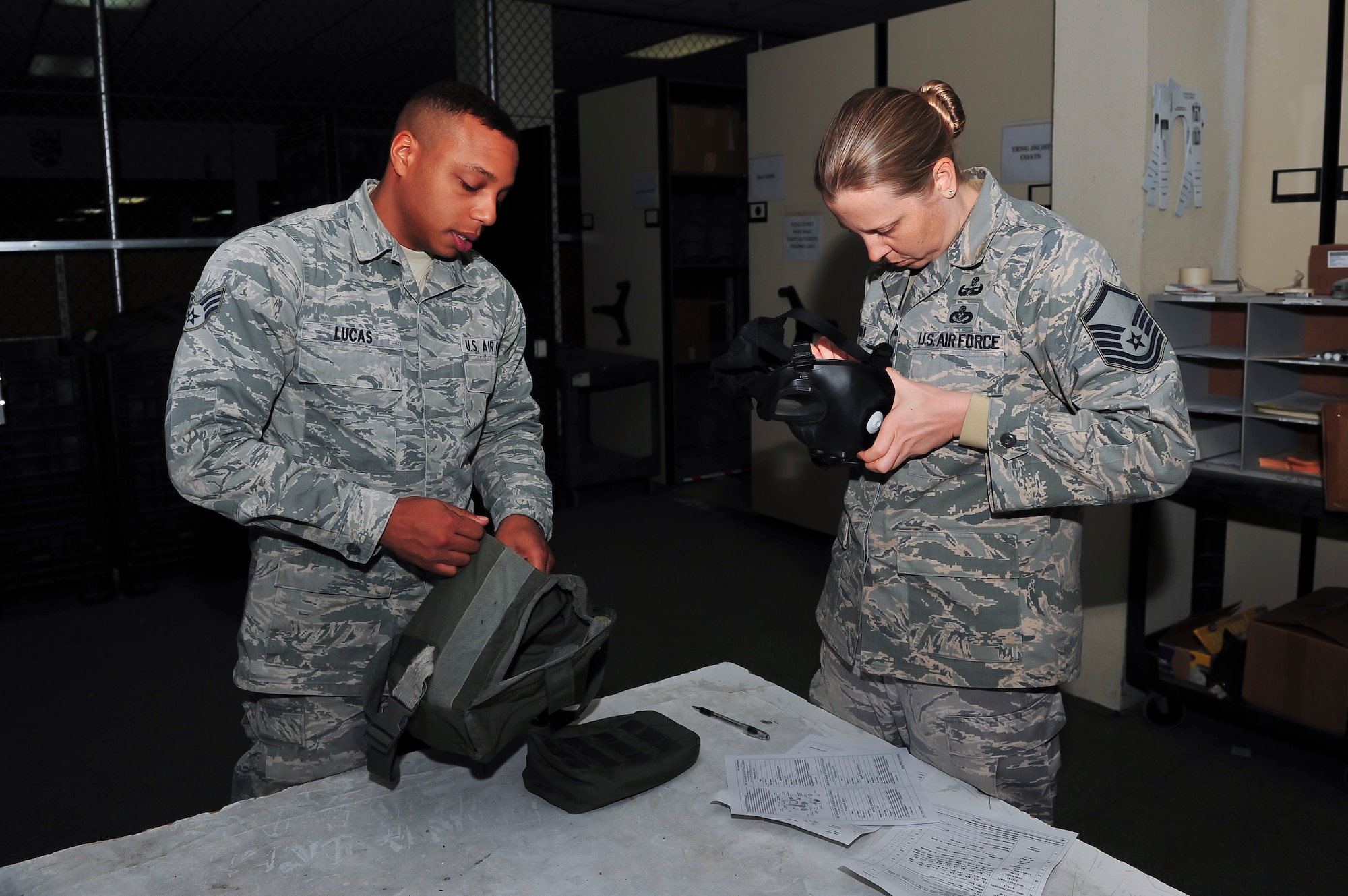 Senior Airman Lorenzo Lucas, 51st Logistic Readiness Squadron individual protective equipment technician, helps Master Sgt. Jen Shanks, 51st Civil Engineer Squadron Explosive Ordinance Disposal flight chief, perform an inspection of a gas mask at the 51st LRS IPE building Jan. 27, 2015, at Osan Air Base, Republic of Korea. All mission essential personnel will receive their gear within the first 10-days upon arriving on station. (U.S. Air Force photo by Senior Airman David Owsianka)