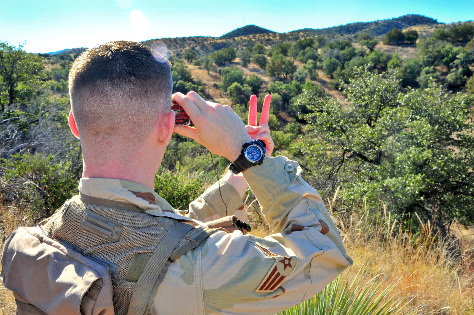 U.S. Air Force Airman 1st Class Andrew Stranger, 355th Operations Support Squadron intelligence analyst, uses a mirror to signal his location to an A-10C Thunderbolt II flying ahead during a joint training exercise at a southern Arizona military training range, Jan. 20, 2015.  Stranger was simulating a downed pilot during the close air support and combat search and rescue training.  (U.S. Air Force Photo by Airman 1st Class Chris Massey/Released)