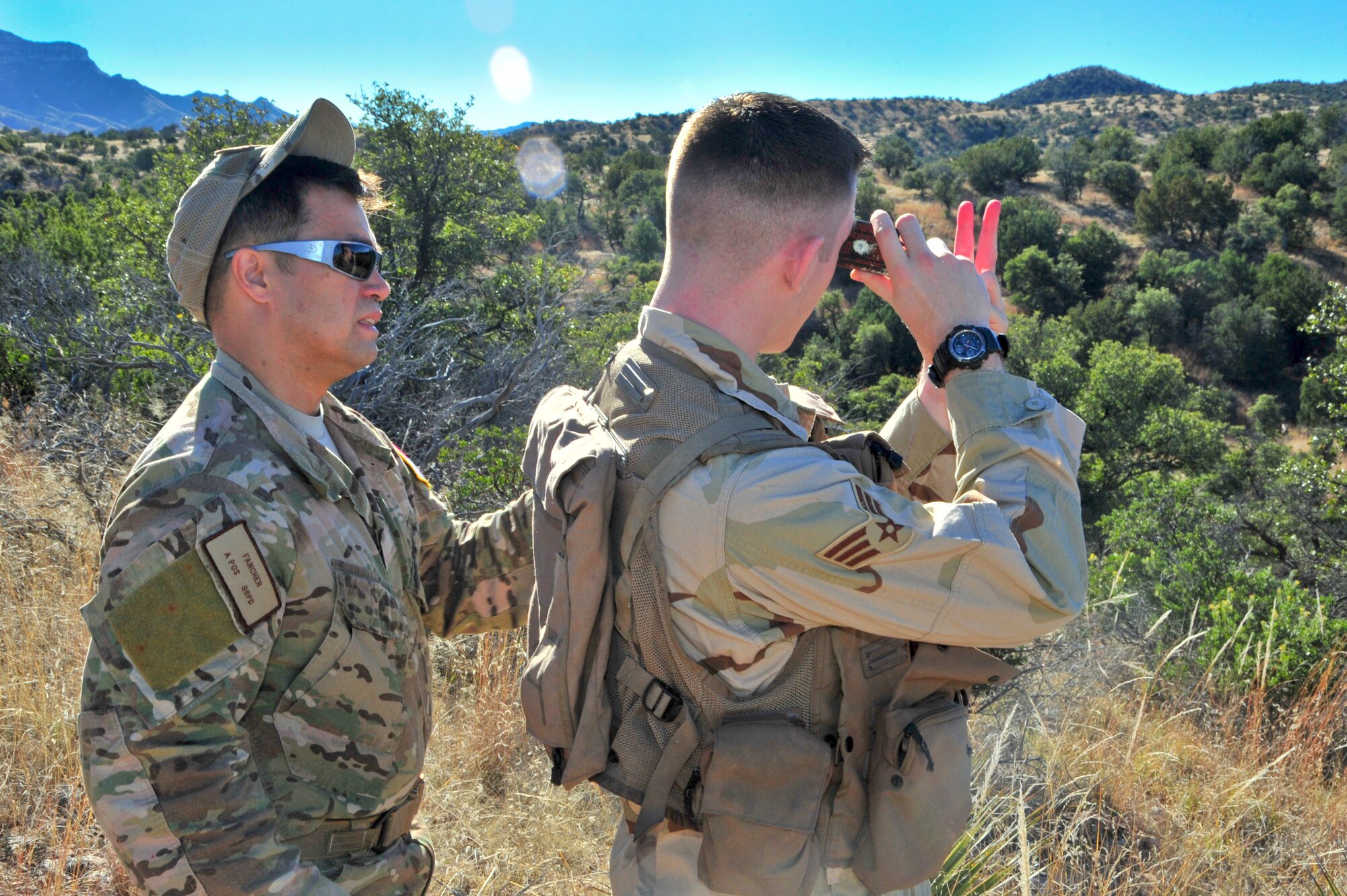 U.S. Air Force Tech. Sgt. Tony Fancher, 355th Operations Support Squadron survival, evasion, resistance and escape specialist, instructs Airman 1st Class Andrew Stranger, 355th Operations Support Squadron intelligence analyst, how to confirm his location with a signal mirror to an A-10C Thunderbolt II flying ahead during a joint training exercise at a southern Arizona military training range, Jan. 20, 2015.  Stranger was simulating a downed pilot during the close air support and combat search and rescue training.  (U.S. Air Force Photo by Airman 1st Class Chris Massey/Released)