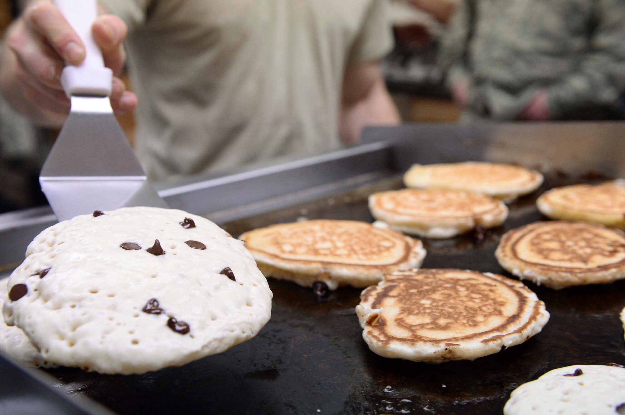 U.S. Air Force 2nd Lt. Eric Millen, the 354th Maintenance Squadron maintenance flight commander, flips chocolate-chip pancakes at the 18th Aircraft Maintenance Unit (AMU) hangars, on Eielson Air Force Base, Alaska, Jan. 15, 2014. Millen and other leaders at the 18th AMU helped with their Airmen's morale by cooking breakfast for maintainers while they worked to launch numerous aircraft simultaneously for a large-scale exercise. (U.S. Air Force Photo by Senior Airman Peter Reft/Released)