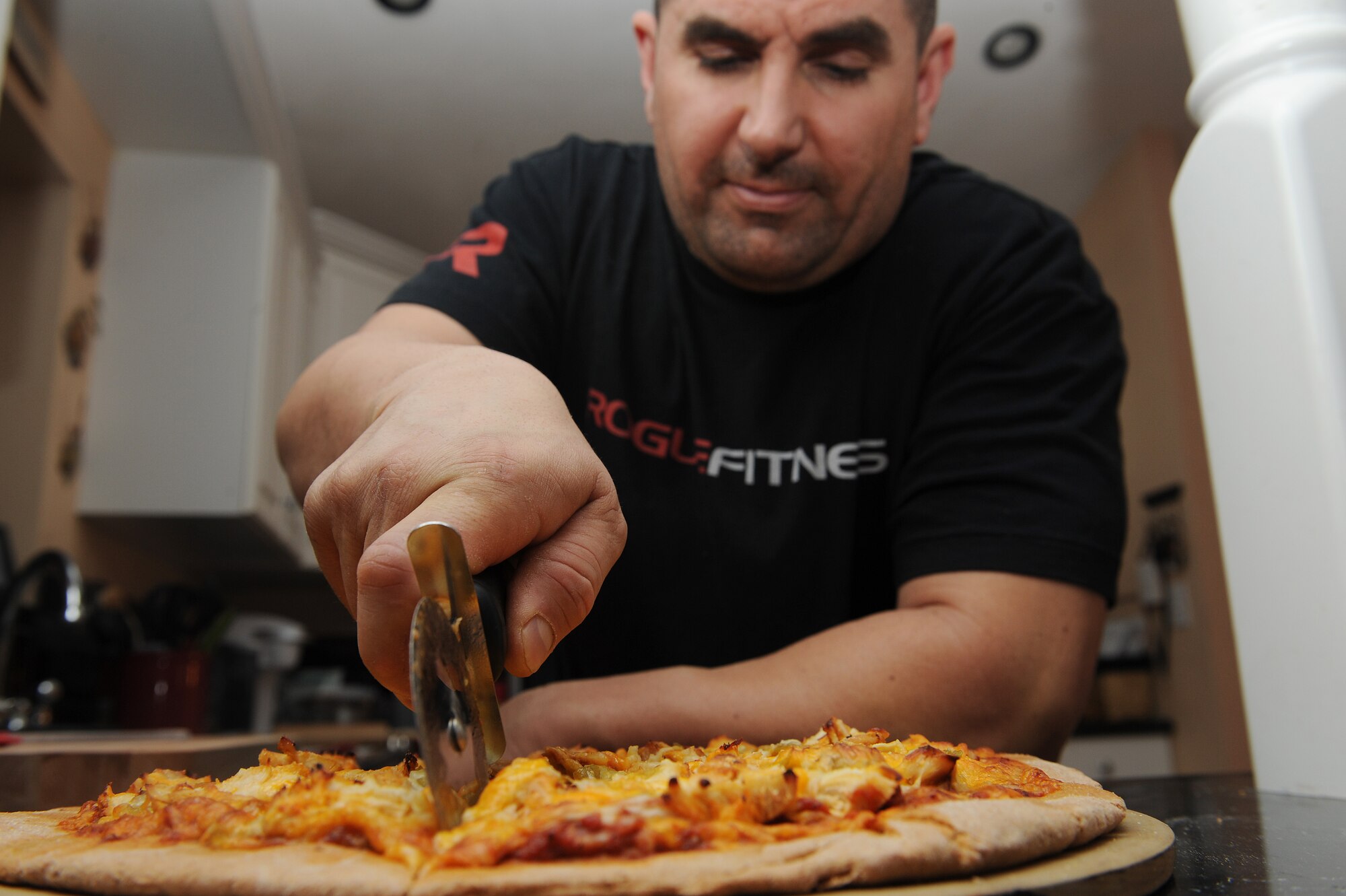 Master Sgt. Scott Stuehrenberg slices his homemade, wheat pizza.  Stuehrenberg uses a wheat-based flower so the pizza will be healthier and have fewer calories.  Stuehrenberg is a 618th Air and Space Operations global operations manager.  (U.S. Air Force photo by Staff Sgt. Maria Bowman)