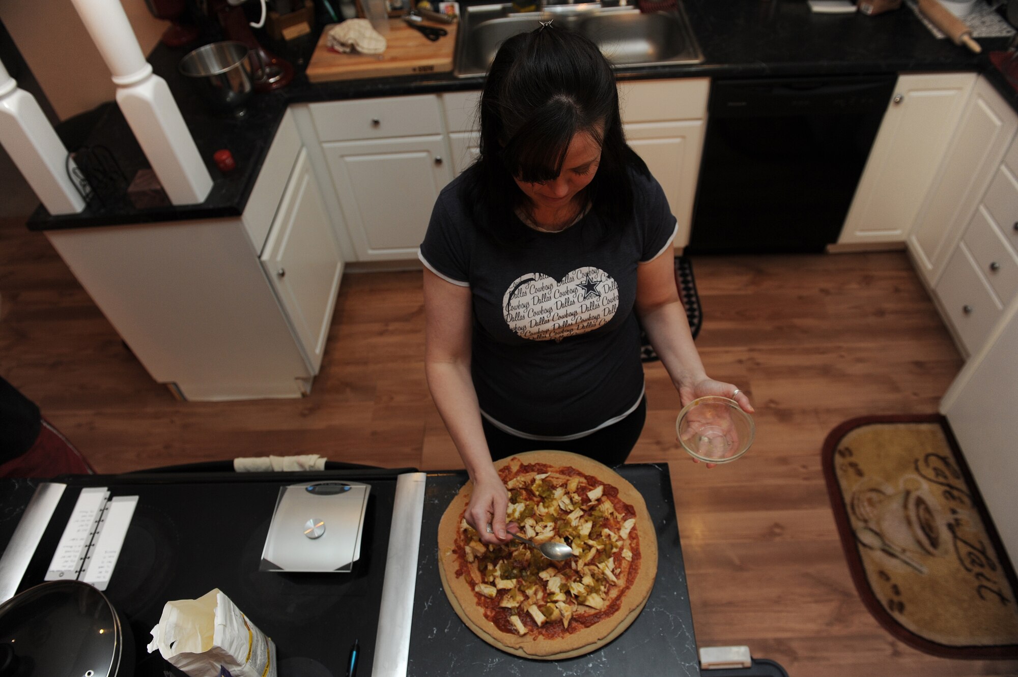 Lisa Stuehrenberg adds toppings to the homemade, wheat pizza.  Stuehrenberg and her husband monitor their calories and make all their meals at home.  She has lost 45 pounds since she began to watch what she ate.  Stuehrenberg is a 618th Air and Space Operations key spouse. (U.S. Air Force photo by Staff Sgt. Maria Bowman)