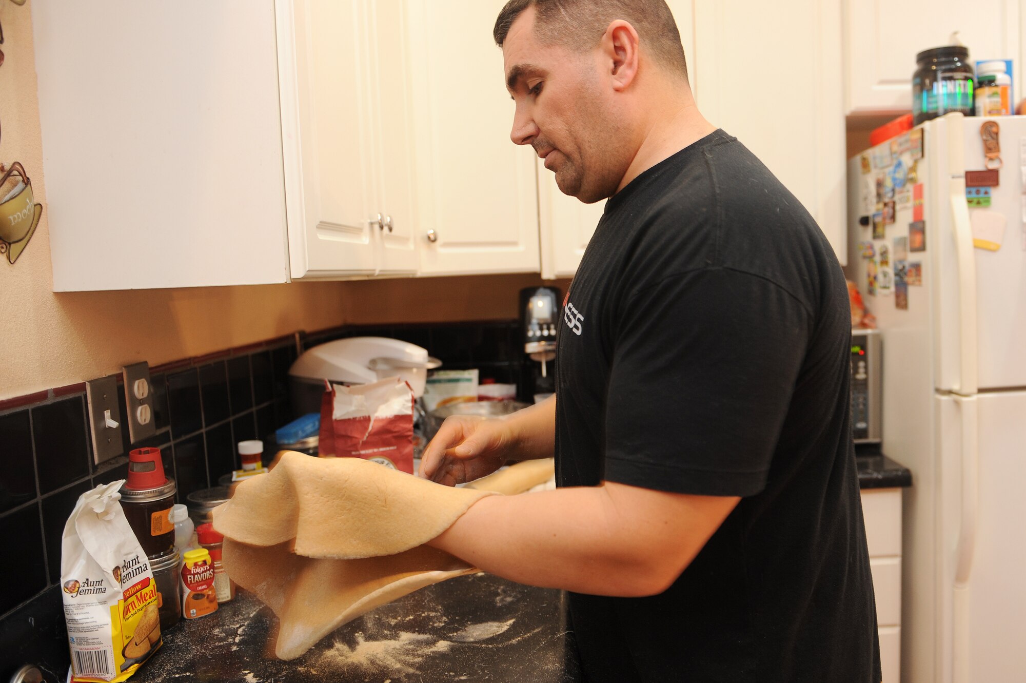 Master Sgt. Scott Stuehrenberg tosses pizza dough, in order to maintain its moisture and keep the crust softer.  Stuehrenberg uses a wheat-based flower so the pizza will be healthier and have fewer calories.  Stuehrenberg is a 618th Air and Space Operations global operations manager.  (U.S. Air Force photo by Staff Sgt. Maria Bowman)