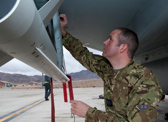 Sgt Euan Fisher, a Royal Air Force weapons technician assigned to 6 Squadron, RAF Lossiemouth, Scotland, conducts armament inspections beneath a Typhoon FGR4 fighter at Nellis Air Force Base, Nev., Jan. 27, 2015. Fisher was preparing the aircraft to receive live ordinance to be used during a Red Flag 15-1 training sortie. (U.S. Air Force photo by Airman 1st Class Joshua Klenholz)