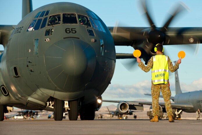 A Royal Australian air force aircraft maintainer marshalls an RAAF C-130J Super Hercules into position after a training mission during Red Flag 15-1 at Nellis Air Force Base, Nev., Jan. 27, 2015. The mock battle training provided by Red Flag in the skies over the Nevada Test and Training Range has yielded results that increase the combat capability of U.S. and allied air forces for future real-world combat situations. (U.S. Air Force photo by Senior Airman Thomas Spangler)