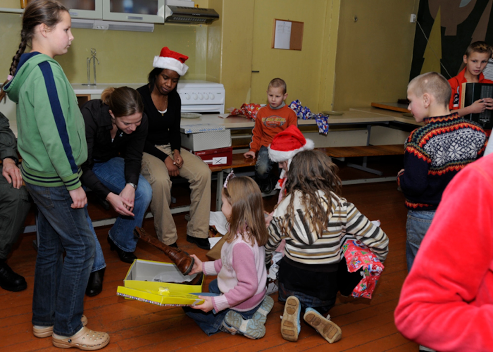Capt. Christina Zimmerman and Staff Sgt. Kaneel Williams, 493rd Expeditionary Fighter Squadron watch children from the Kelme District Vijurkai Children’s Home open their gifts Dec. 19 in Lithuania. More than 100 Airmen supporting the NATO Baltic Air Policing mission in Siauliai, Lithuania threw a holiday party for the children to spread their generosity and holiday cheer. (U.S. Air Force photo by Airman 1st Class Torri K. Larson/Released)