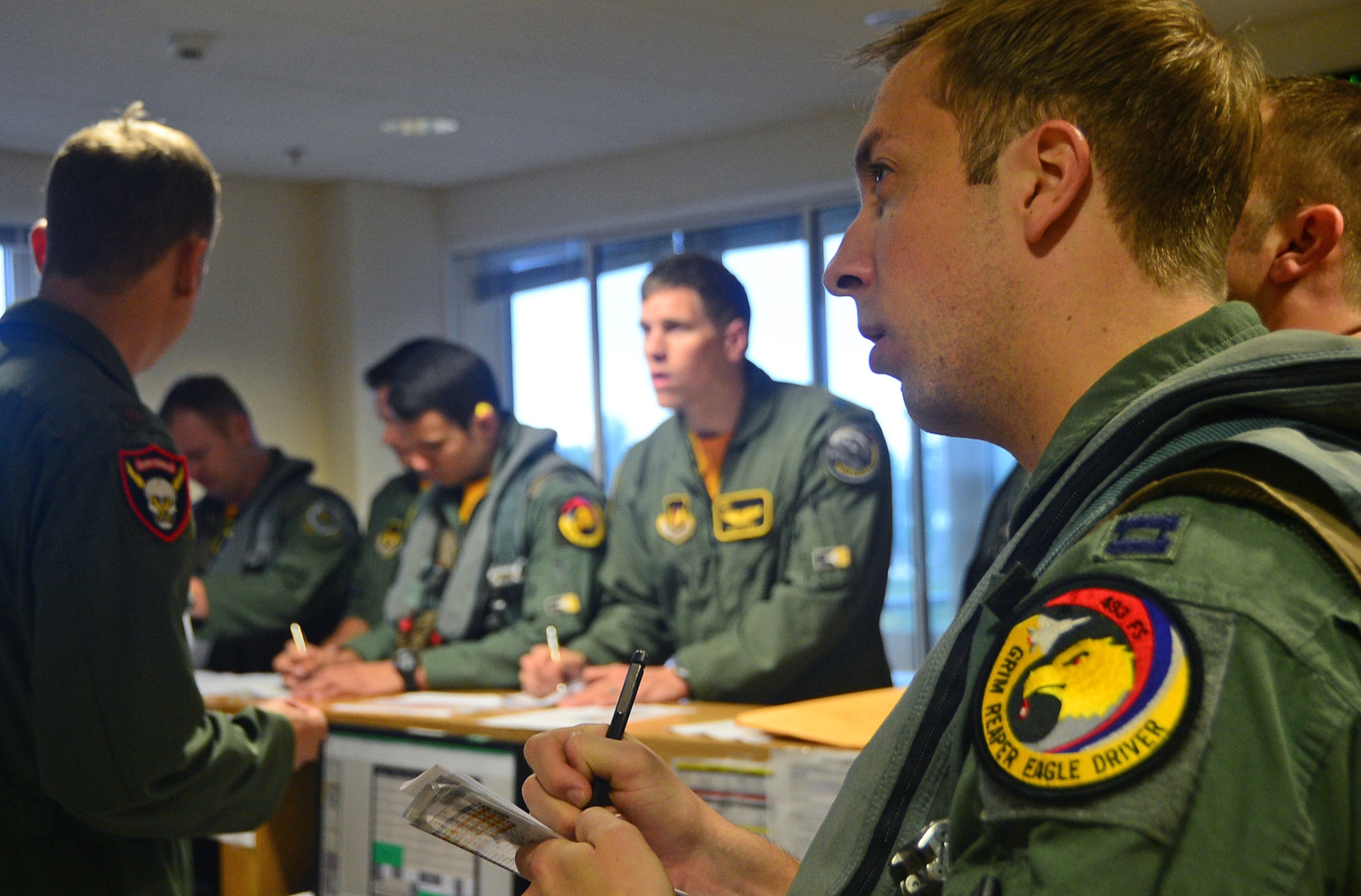 F-15C Eagle fighter pilots assigned to the 493rd Fighter Squadron take notes during a brief before departing Royal Air Force Lakenheath, England, Aug. 15, 2014, for a bilateral training event. The F-15 fighter pilots’ flying training deployment to Bulgaria focused on maintaining joint readiness while building interoperable capabilities. (U.S. Air Force photo by Senior Airman Erin O’Shea/Released)