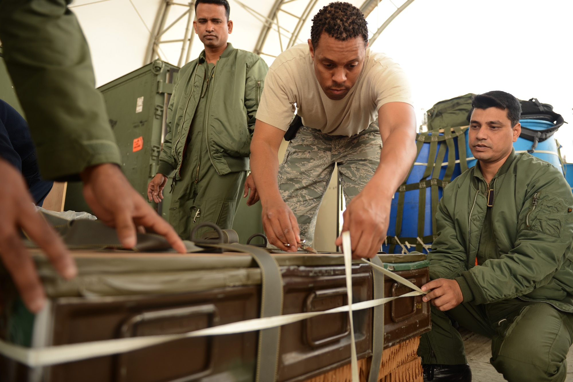 U.S. Air Force Staff Sgt. Wantani Redo demonstrates low-cost, low-altitude airdrop bundle rigging procedures to Bangladesh Air Force personnel from the 101st Special Flying Unit during a subject matter expert exchange at Exercise COPE SOUTH, BAF Base Bangabandhu, Jan. 27, 2015. Redo is assigned to the 374th Logistics Readiness Squadron, Combat Mobility Flight, Yokota Air Base, Japan. COPE SOUTH is a Pacific Air Forces-sponsored, bilateral tactical airlift exercise conducted in Bangladesh, with a focus on cooperative flight operations, day and night low-level navigation, tactical airdrop, and air-land missions as well as subject-matter expert exchanges in the fields of operations, maintenance and rigging disciplines. COPE SOUTH helps cultivate common bonds, foster goodwill, and improve readiness and compatibility between members of the Bangladesh and U.S. Air Forces. (U.S. Air Force photo by 1st Lt. Jake Bailey/Released)