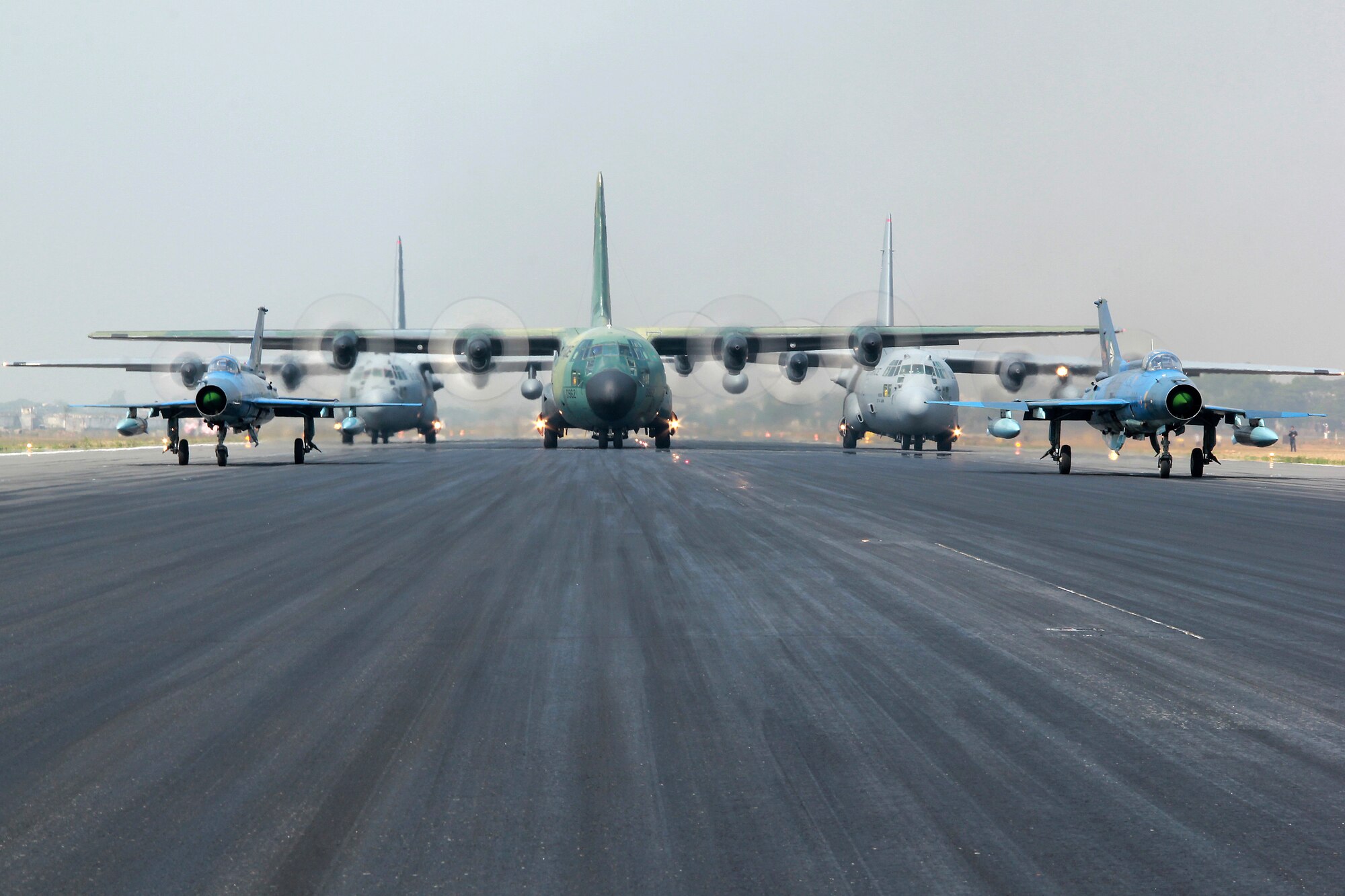 Two Bangladesh F-7BG Defenders, a BAF C-130B Hercules, and two U.S. Air Force C-130H Hercules aircraft prepare to take off from BAF Base Bangabandhu,  Bangladesh, during Exercise COPE SOUTH Jan. 28, 2015. The U.S. C-130H is assigned to the 374th Airlift Wing, Yokota Air base, Japan; the BAF F-7BGs are assigned to 5th Squadron and the BAF C-130B is assigned to 101st Special Flying Unit at BAF Base Bangabandhu. COPE SOUTH is a Pacific Air Forces-sponsored, bilateral tactical airlift exercise conducted in Bangladesh, with a focus on cooperative flight operations, day and night low-level navigation, tactical airdrop, and air-land missions as well as subject-matter expert exchanges in the fields of operations, maintenance and rigging disciplines. (Courtesy photo by Bangladesh Air Force)