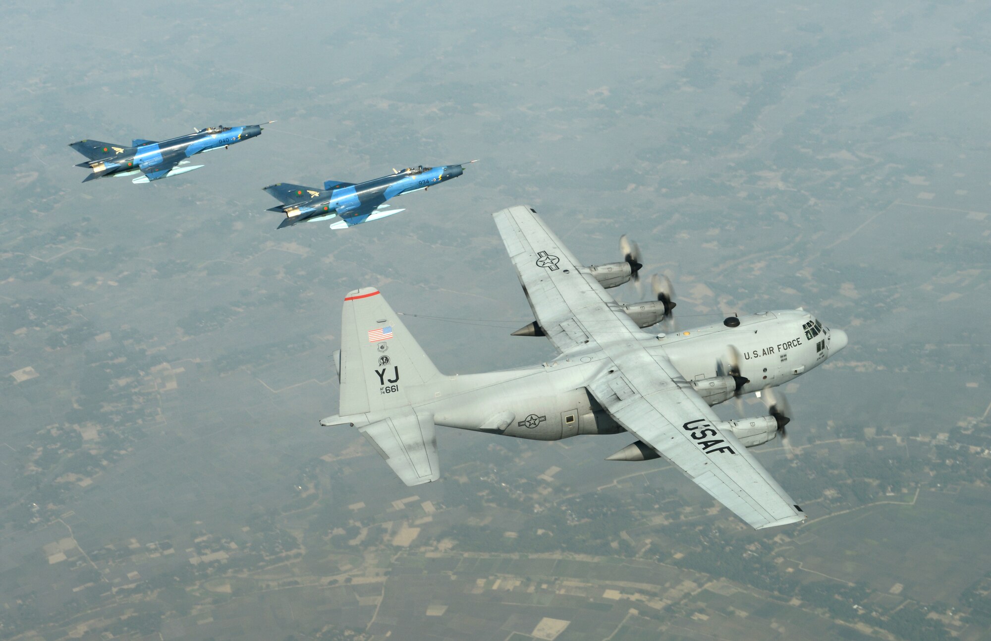 Two Bangladesh Air Force F-7BG Defenders from 5th Squadron, BAF Base Bangabandhu, escort a U.S. C-130H Hercules from the 374th Airlift Wing, Yokota Air Base, Japan, during Exercise COPE SOUTH near Kishoreganj, Bangladesh, Jan. 28, 2015. COPE SOUTH is a Pacific Air Forces-sponsored, bilateral tactical airlift exercise conducted in Bangladesh, with a focus on cooperative flight operations, day and night low-level navigation, tactical airdrop, and air-land missions as well as subject-matter expert exchanges in the fields of operations, maintenance and rigging disciplines. (U.S. Air Force photo by 1st Lt. Jake Bailey/Released)