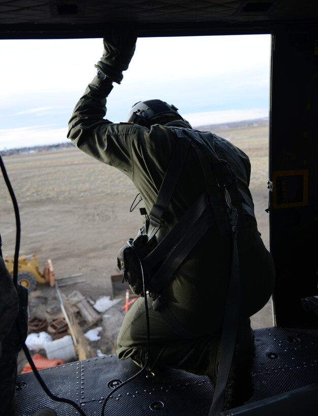 Staff Sgt. Ryan Oliver, 40th Helicopter Squadron special missions aviator, looks below his UH-1N Huey as its pilot tries to line it up for a hover over a structure Jan. 27, 2015, at Malmstrom Air Force Base, Mont. The crew was practicing some low-level maneuvers to keep their skills sharp. (U.S. Air Force photo/ Airman 1st Class Dillon Johnston)