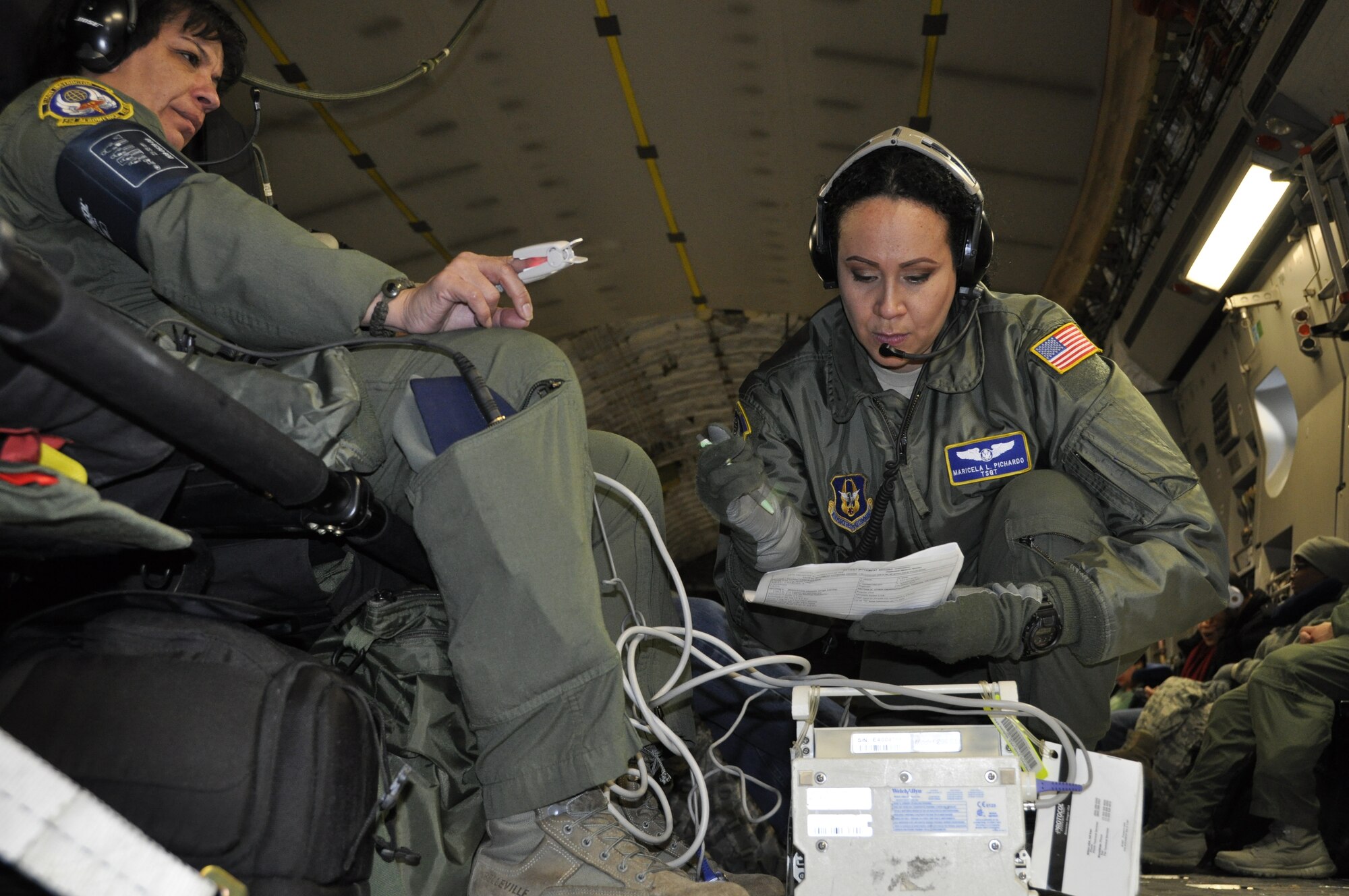 Medical Technician, Tech. Sgt. Maricela Pichard, right, reviews a checklist, while taking the blood pressure or vitals(?) of a simulated asthmatic patient, played by nurse instructor, Maj. Rosa Ramos, during a training mission on board a C-17 Jan. 17-19. Both are reservists assigned to the 514th Aeromedical Evacuation Squadron at Joint Base McGuire-Dix-Lakehurst, N.J. (Air Force photo/Master Sgt. Donna T. Jeffries)