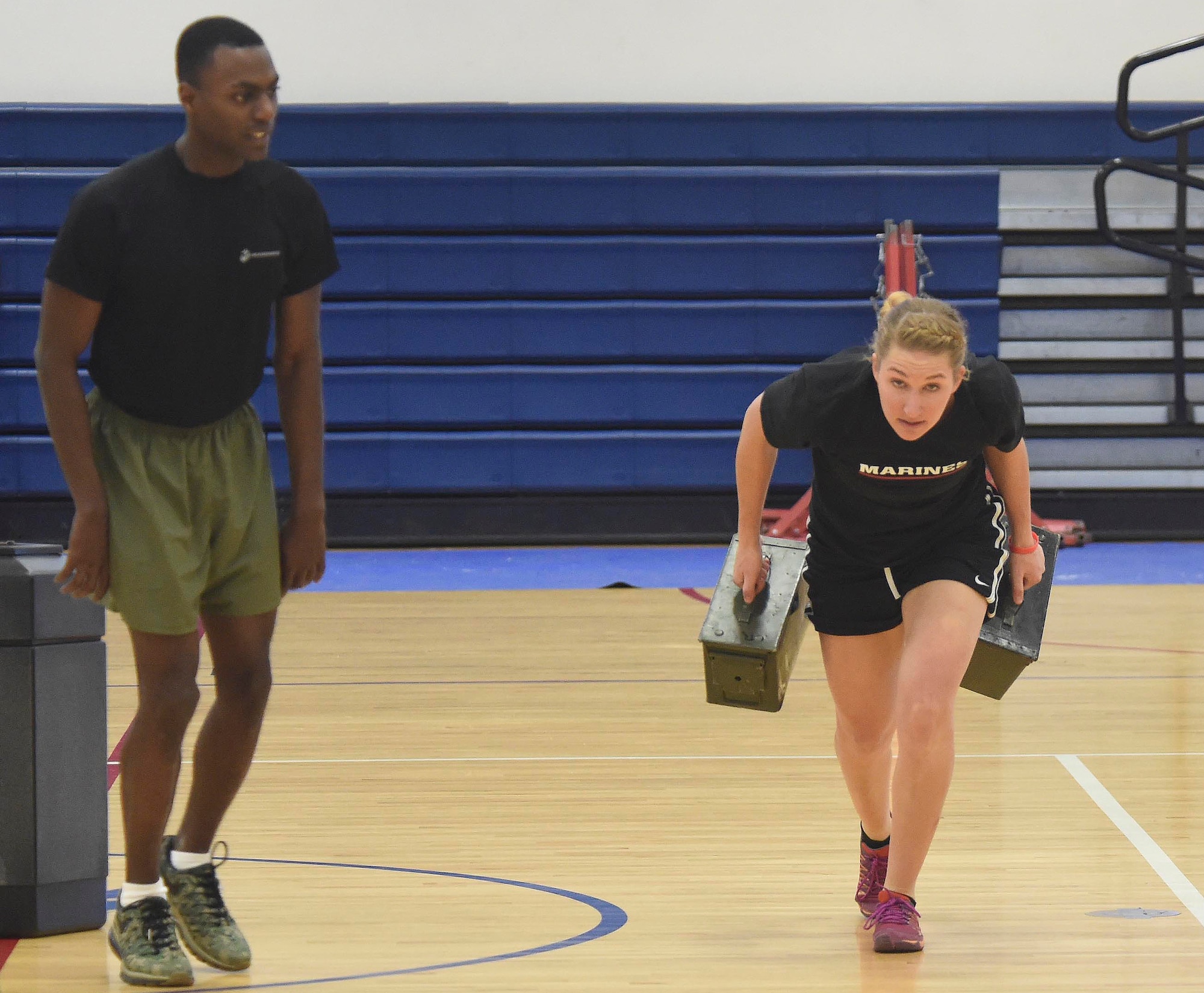 A U.S. Marine Corps poolee sprints with an ammunition can while a Marine instructs during a delayed entry program all-female workout held Jan. 17, 2015, at the fitness center on Buckley Air Force Base, Colo. Poolees are members of the DEP that have not yet shipped out to recruit training. The DEP workouts consist of strengthening exercises such as pull-ups, box jumps, push-ups and squats to enable poolees to be accustomed to the vigorous workouts and stress they will endure during recruit training. (U.S. Air Force photo by Airman 1st Class Samantha Saulsbury/Released)