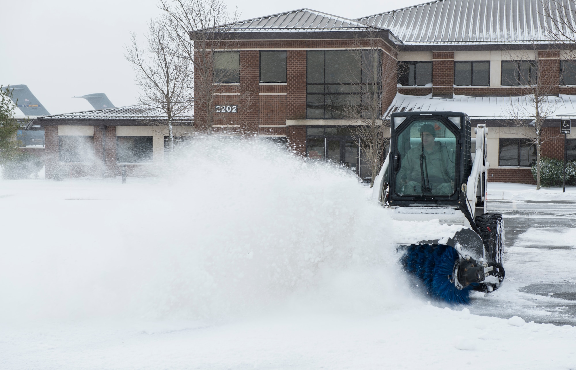 An 87th Civil Engineer Squadron Airman clears snow from a parking lot on Joint Base McGuire-Dix-Lakehurst, N.J., Jan. 27, 2015. The 87th CES members worked 12 hour shifts to prepare for and then clean up after Winter Storm Juno. (U.S. Air Force photo by Airman 1st Class Joshua D. King/Released)