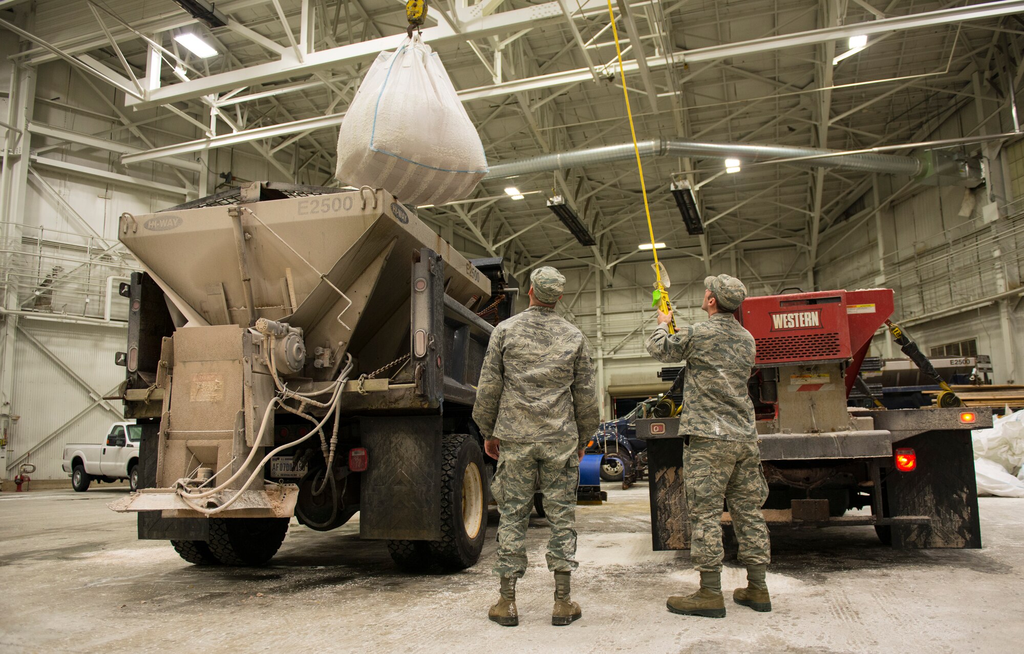 Airmen 1st Class Joseph Betal and Nickalas Boomershine, 87th Civil Engineer Squadron technicians, maneuver a bag of salt on to the top of a salt truck on Joint Base McGuire-Dix-Lakehurst, N.J., Jan. 26, 2015. The 87th CES members worked 12 hour shifts to prepare for and then clean up after Winter Storm Juno. (U.S. Air Force photo by Airman 1st Class Joshua D. King/Released)