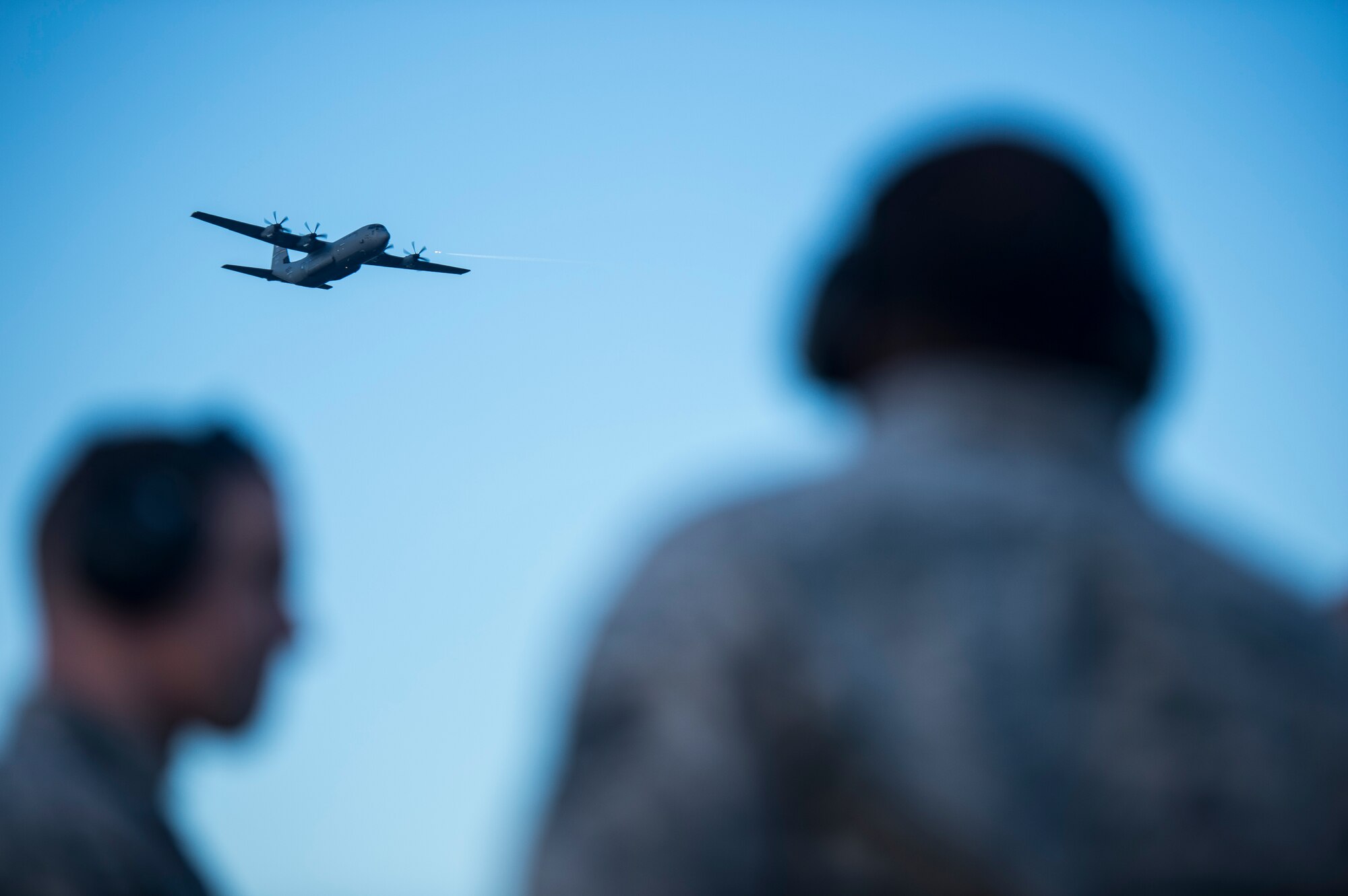 A C-130J flies over the heads of 19th Logistic Readiness Squadron Airmen as they upload equipment into a C-130 Jan. 16, 2015, at Little Rock Air Force Base, Ark. The Airmen were participating in Green Flag Little Rock 15-01. (U.S. Air Force photo/Senior Airman Cliffton Dolezal)