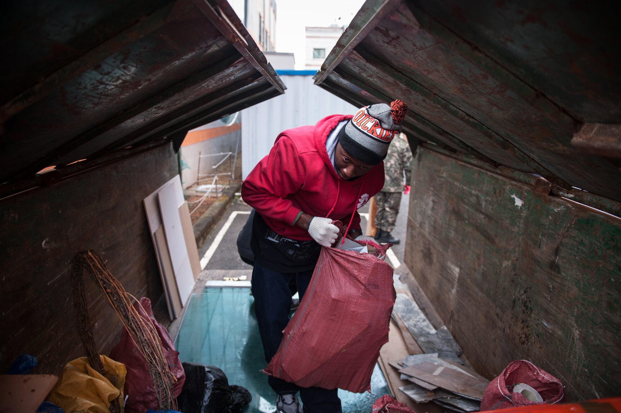 Senior Airman Patrick Moton, 80th Fighter Squadron aviation resource manager, throws trash into a dumpster outside the Gunsan City Rehabilitation Center in Gunsan City, Republic of Korea, Jan. 22, 2015. Wolf Pack Airmen and ROK Air Force members volunteered their day to help at the rehabilitation center. (U.S. Air Force photo by Senior Airman Taylor Curry/Released) 