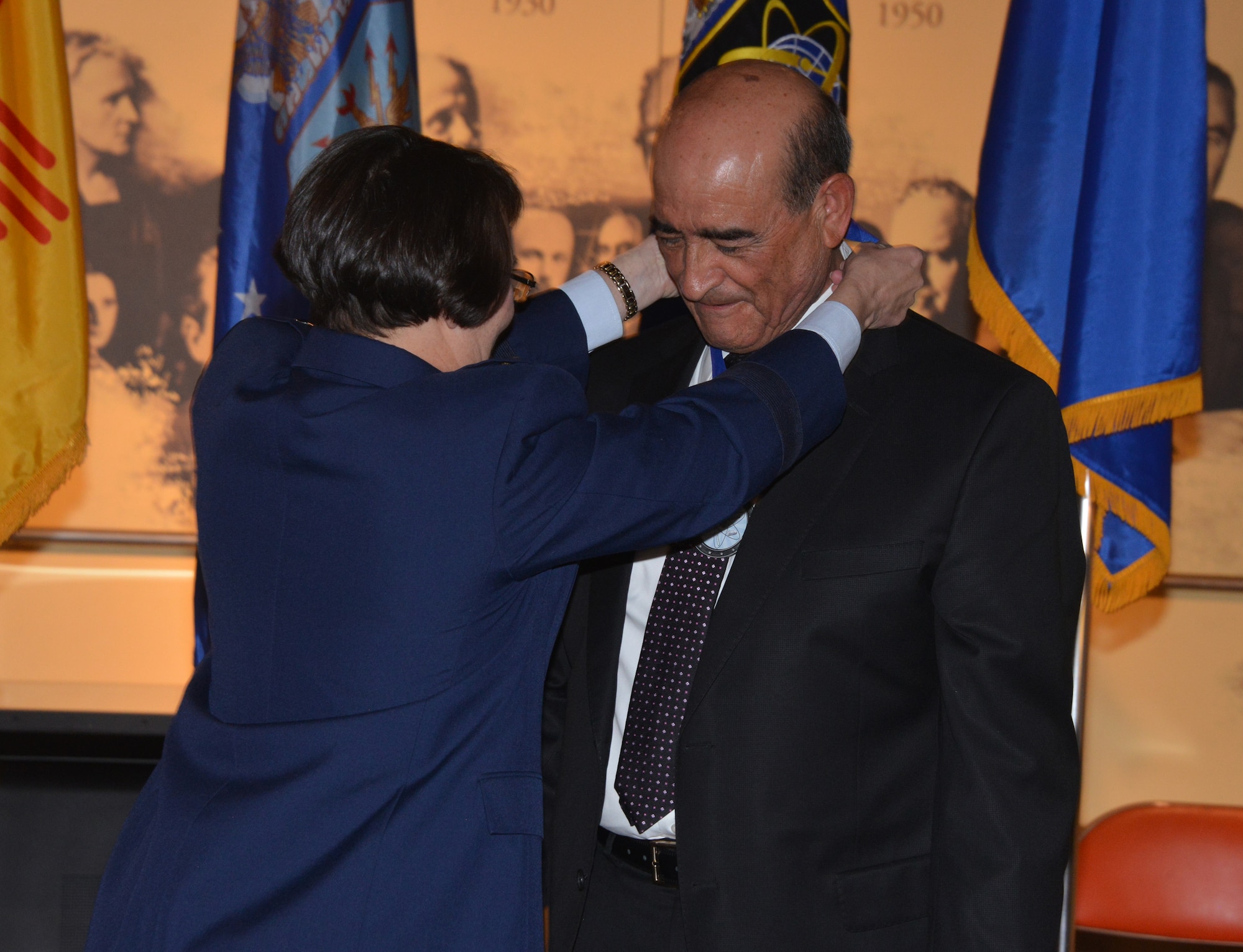 Alex Romero, president and CEO of Albuquerque Hispano Chamber of Commerce receives an Order of the Nucleus medallion from Maj. Gen. Sandra Finan, Air Force Nuclear Weapons Center commander, at a ceremony at the National Museum of Nuclear Science and History Jan. 26. The AFNWC established the Order of the Nucleus in 2011 to recognize and honor individuals and groups who have made significant contributions to the nuclear enterprise of the United States.  (Photo by Dennis Carlson)