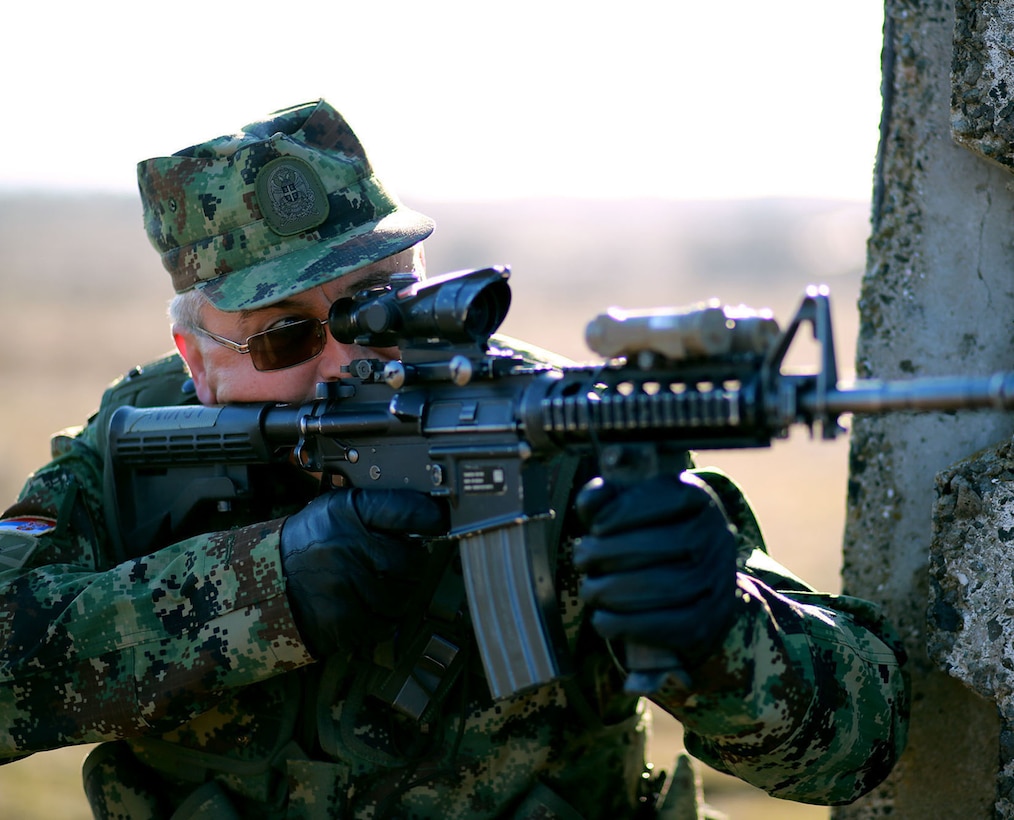 Master Sgt. Ivan Tucic, a Serbian soldier, peaks around a wall at the military operations on urbanized terrain course. Serbians conducted MOUT training with Marines at Novo Selo training area in Bulgaria, Jan. 17, 2015, as part of Exercise Platinum Lion.