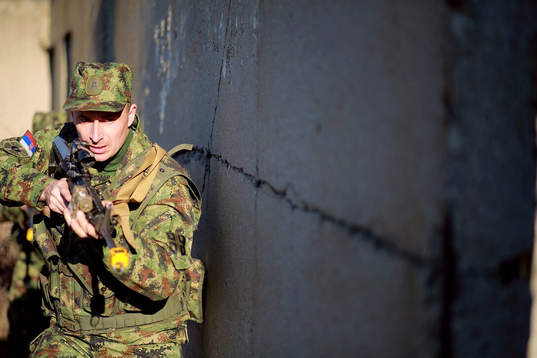 Cpl. Damir Sokac, a Serbian soldier, cautiously approaches an entryway into a building at the military operations on urbanized terrain course. Serbians conducted MOUT training with Marines at Novo Selo training area in Bulgaria, Jan. 17, 2015, as part of Exercise Platinum Lion.