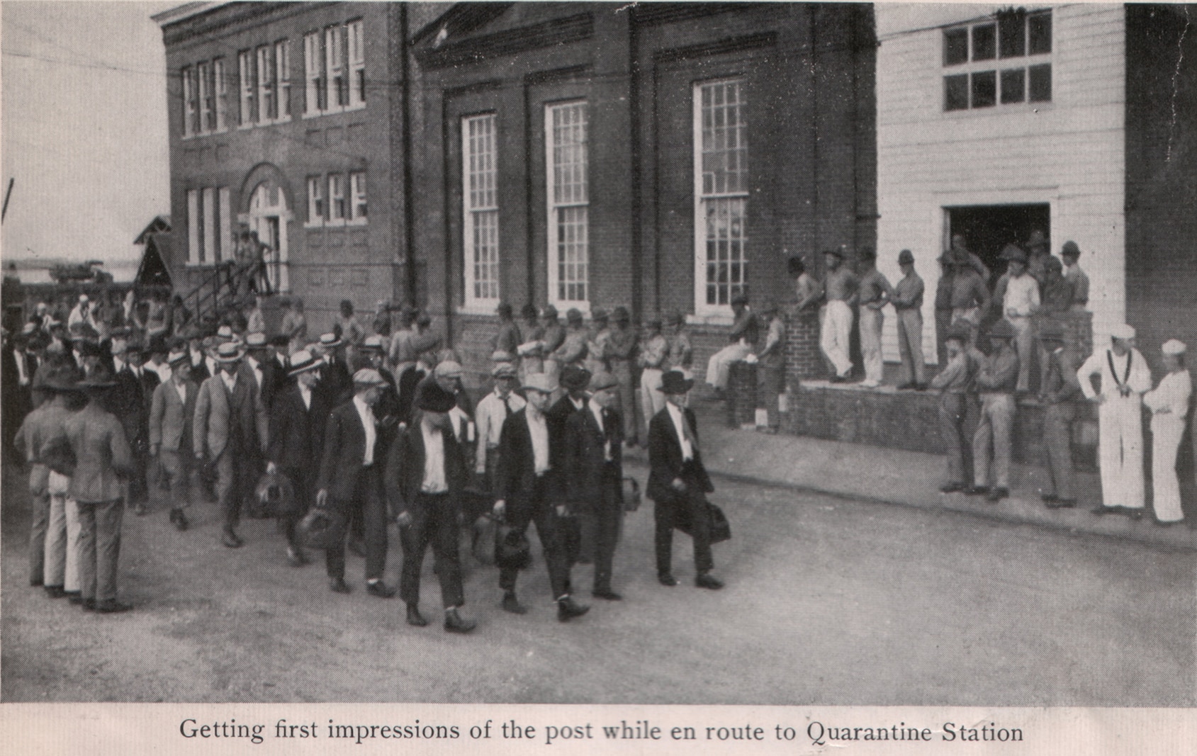 During World War I, recruits arrived at Yemassee and then took a train to Port Royal where they were conveyed to Parris Island by boat or barge to be quarantined. Cleanliness and personal hygiene were stressed. In 1918, the Marines were said to be not only the "first to fight," they were also the "first to clean." This photograph shows recruits marching from the Depot’s main dock past Buildings 17 (the Depot’s original Headquarters Building) and 18 (today the Lyceum).