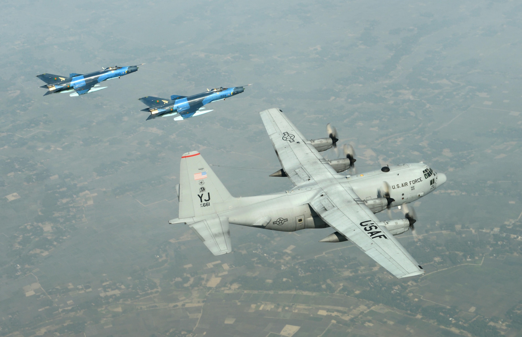 Two Bangladesh air force F-7BG Defenders escort a U.S. Air Force C-130H Hercules during Cope South 15 Jan. 28, 2015, near Kishoreganj, Bangladesh. Cope South is a Pacific Air Forces-sponsored, bilateral tactical airlift exercise conducted in Bangladesh, with a focus on cooperative flight operations, day and night low-level navigation, tactical airdrop, and air-land missions; as well as subject matter expert exchanges in the fields of operations, maintenance and rigging disciplines. The F-7Bs are assigned to the 5th Squadron at BAF Base Bangabandhu, Bangladesh. The C-130H is assigned to the 374th Airlift Wing at Yokota Air Base, Japan. (U.S. Air Force photo/1st Lt. Jake Bailey)