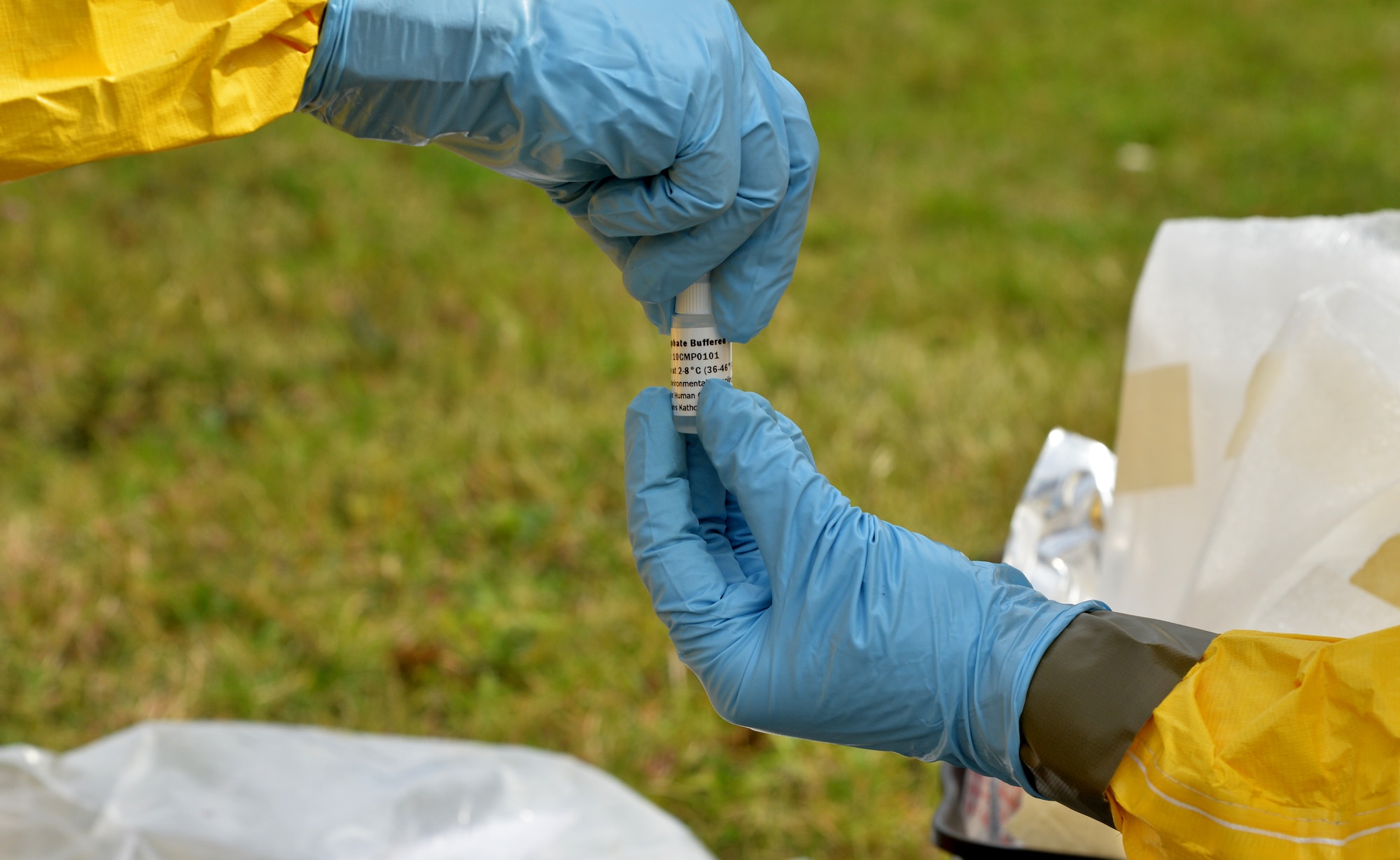 Two 15h Aerospace Medicine Squadron bioenvironmental engineering flight Airmen pass a solution used to test for chemical contamination during integrated base emergency response capability training Jan. 30, 2015, at Joint Base Pearl Harbor-Hickam, Hawaii. The bioenvironmental engineering flight participated in the training Jan. 26-30. (U.S. Air Force photo by Staff Sgt. Alexander Martinez)